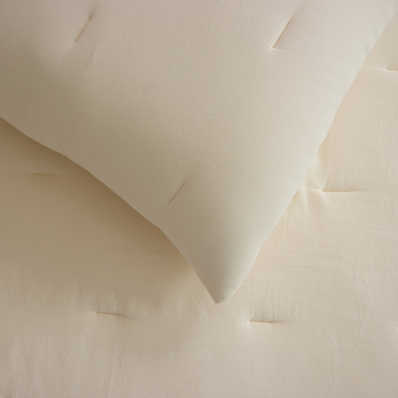 Close up of Buttermilk Aire Bamboo Puckered Shams. The shams are resting on a bed in a bedroom