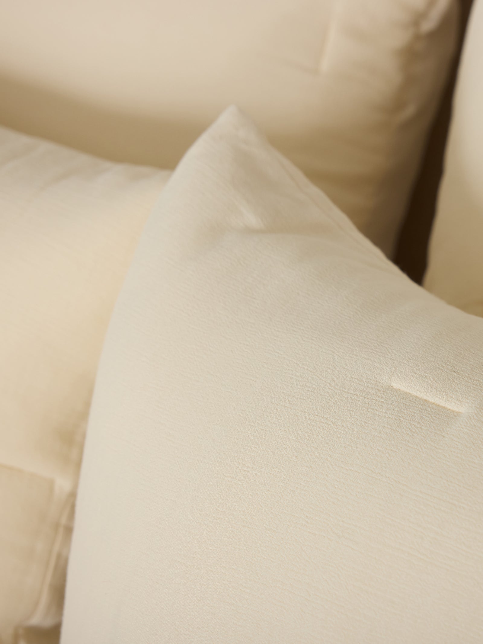 Close up of Buttermilk Aire Bamboo Puckered Shams. The shams are resting on a bed in a bedroom