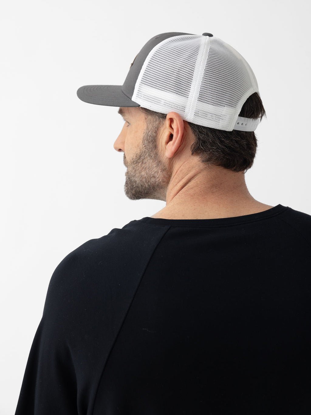 Side and back view of man wearing charcoal/white diamond mesh trucker hat