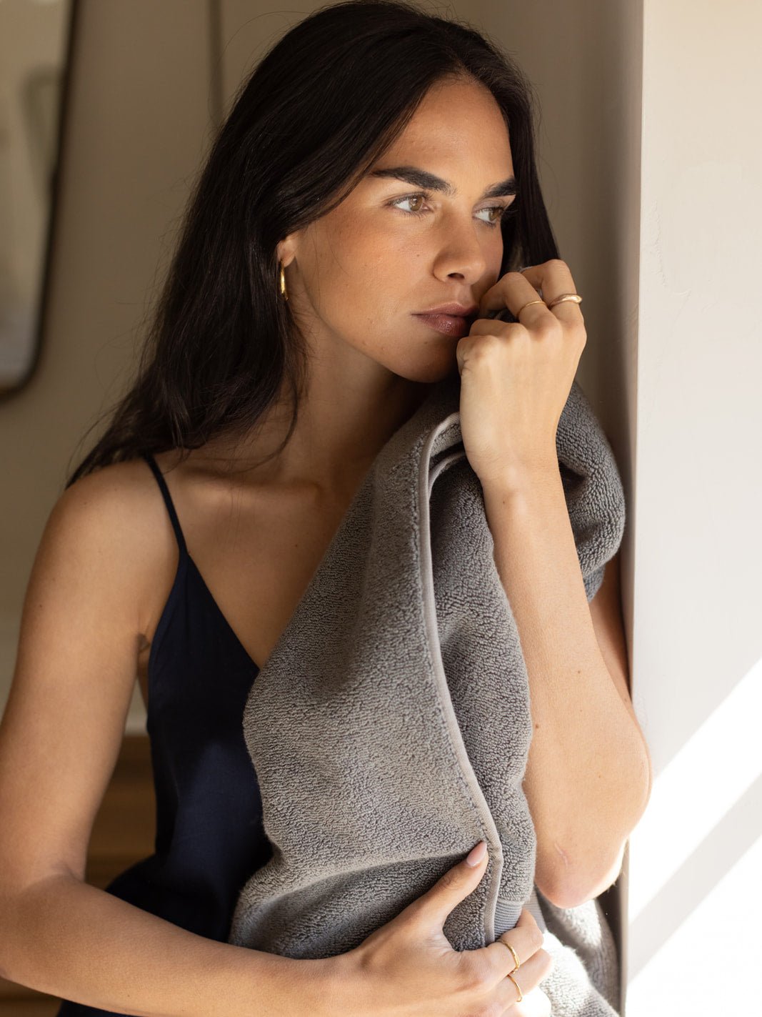 Woman holding charcoal luxe bath towel against her face
