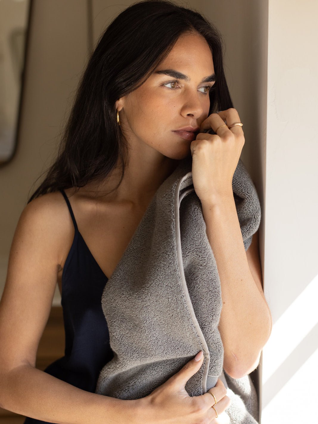 Woman holding charcoal luxe bath towel against her face 