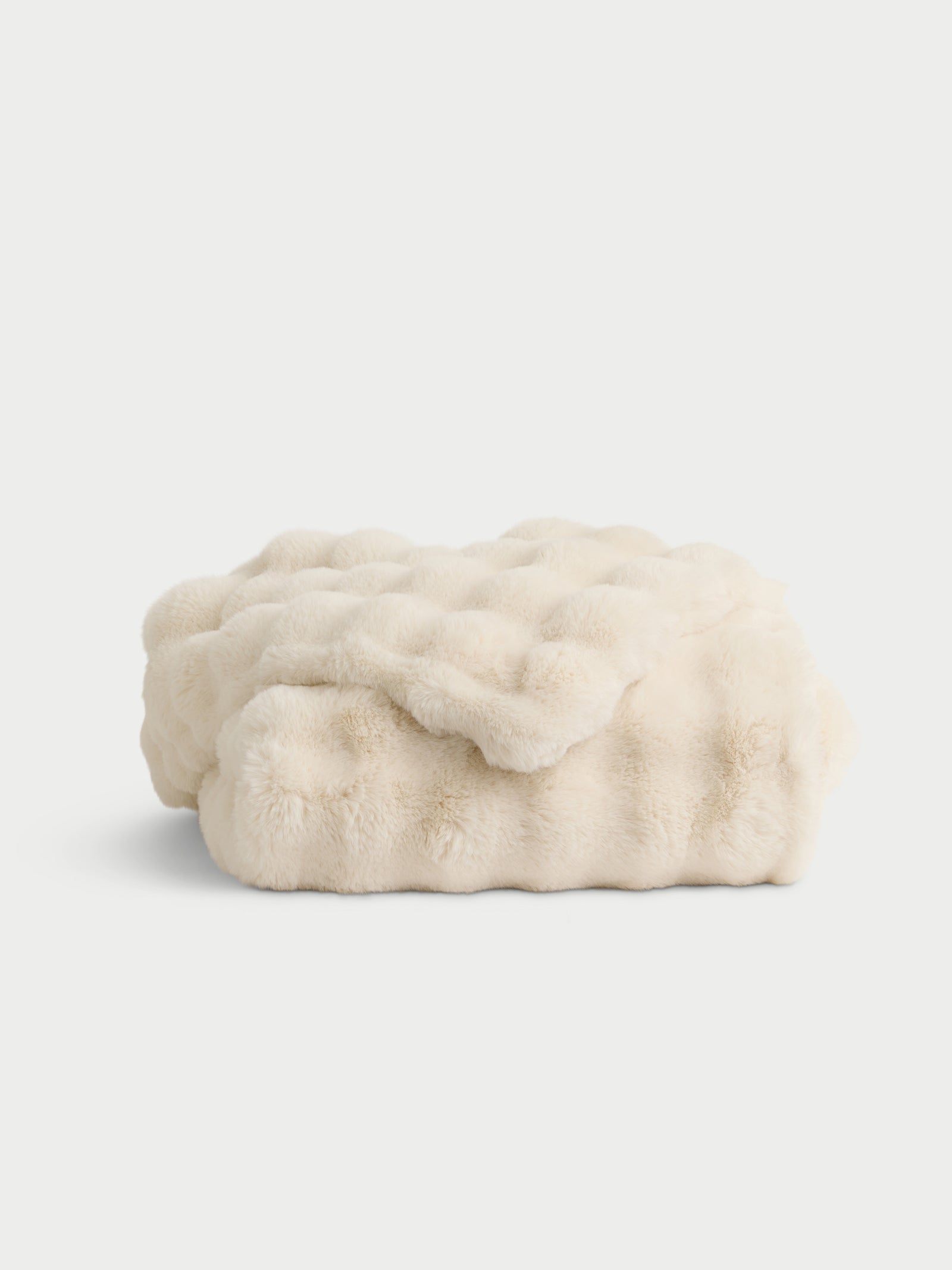 Creme lush faux fur blanket folded with white background 