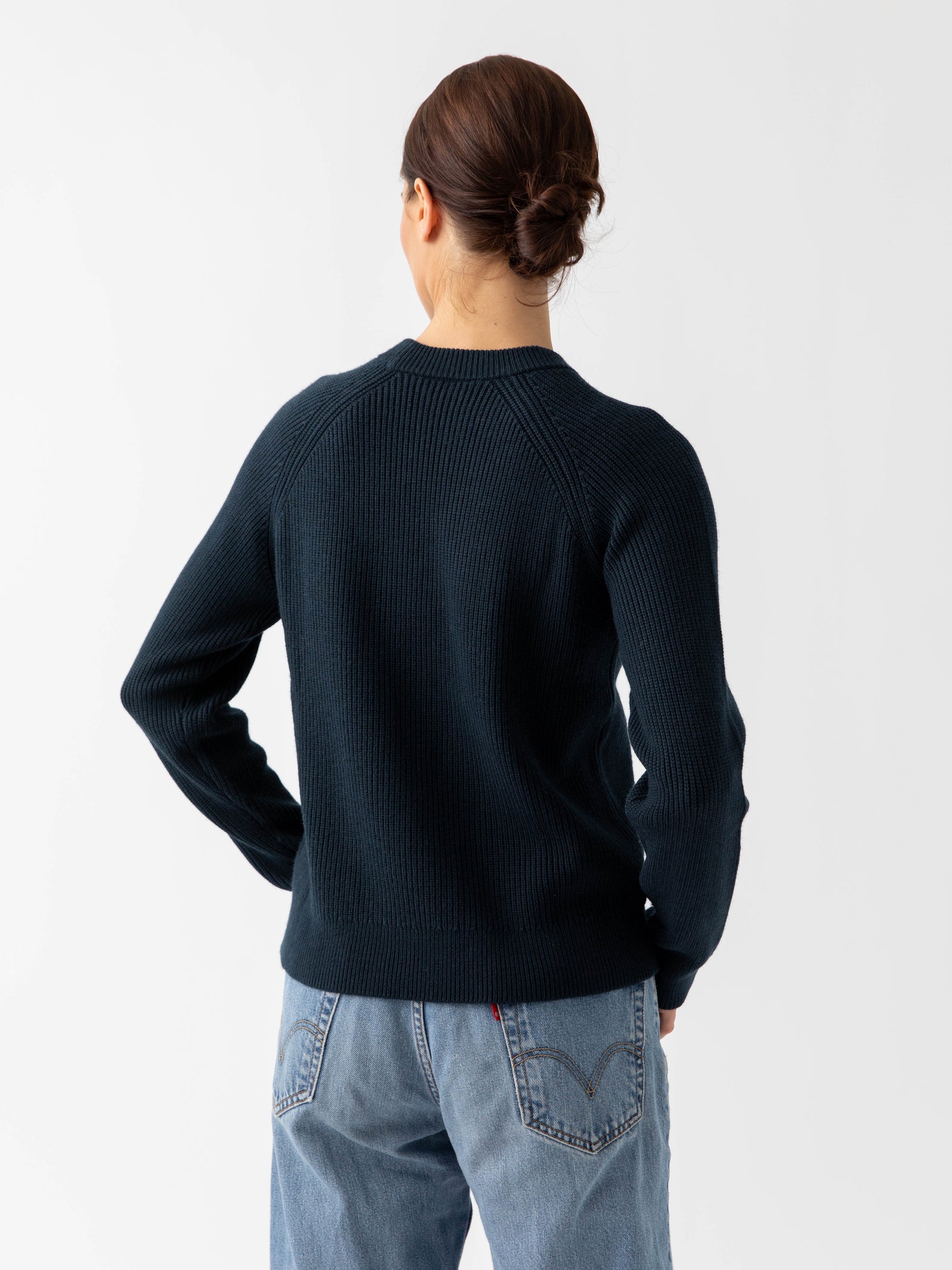Back of woman wearing eclipse classic crewneck and jeans with white background