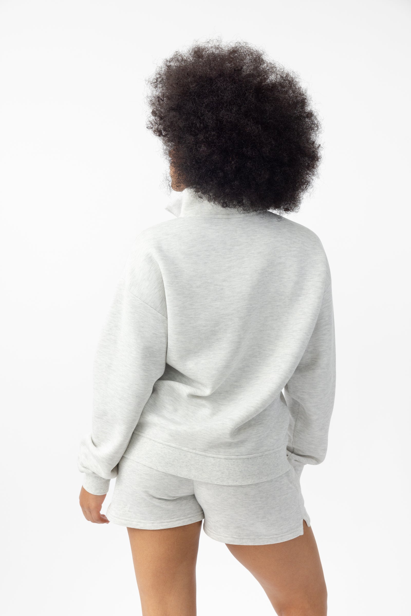 Heather Grey CityScape Quarter Zip. The quarter zip is being worn by a female model. The model is wearing accompanying CityScape clothing to complete the look of the quarter zip. The photo was taken with a white background.