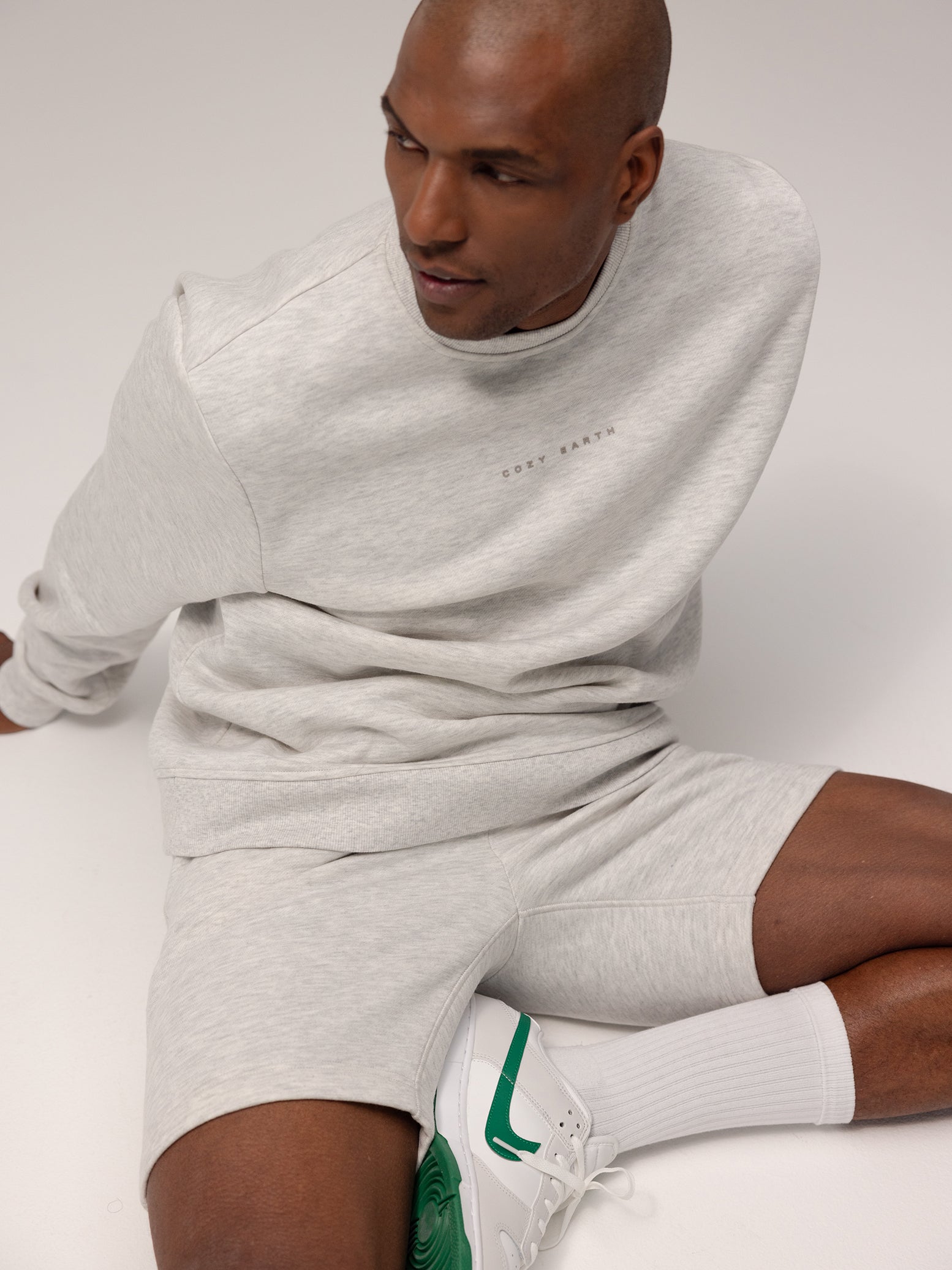 Man sitting on ground wearing heather grey cityscape pullover and shorts