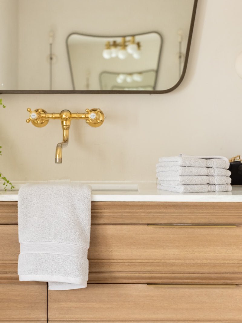 Light grey luxe washcloths and hand towel on bathroom sink 