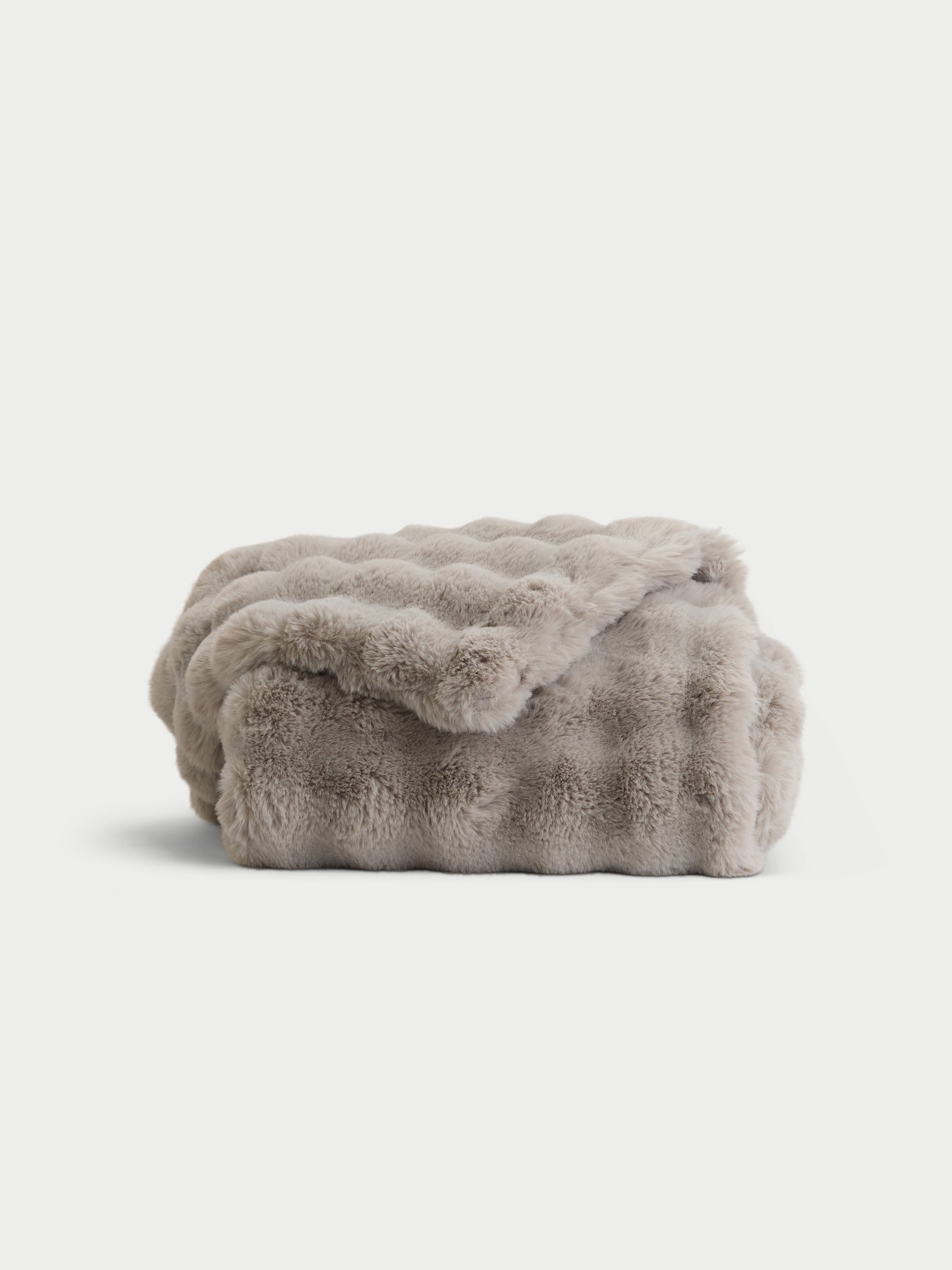 Light grey lush faux fur blanket folded with white background 