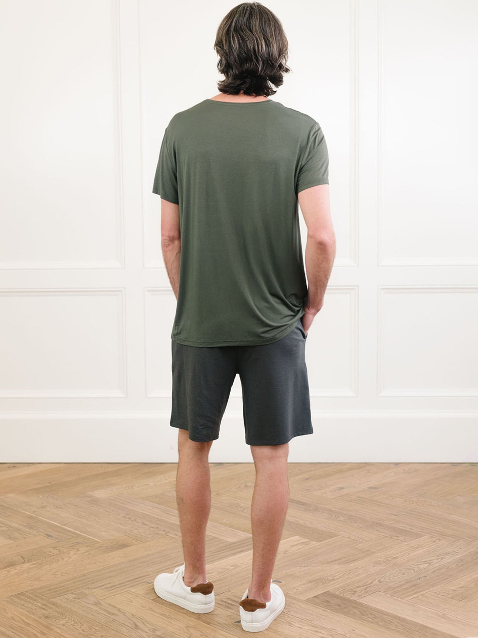 Olive Men's Stretch-Knit Bamboo Lounge Tee. A man is wearing the lounge tee in a well lit home with his back facing the camera.