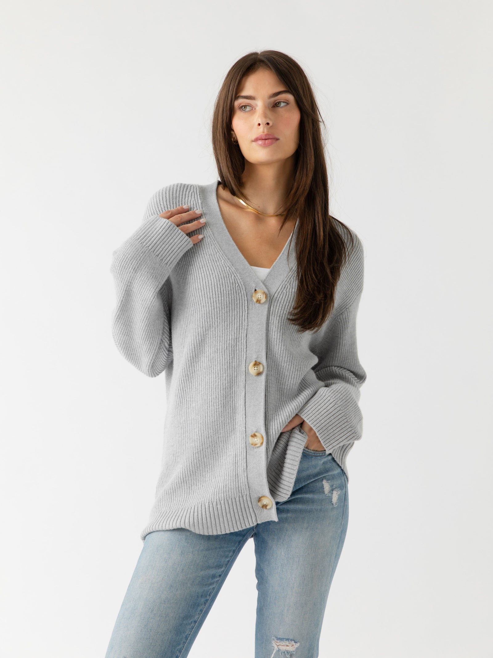 A woman wearing Cozy Earth Classic Cardigan in grey stands in front of a white background