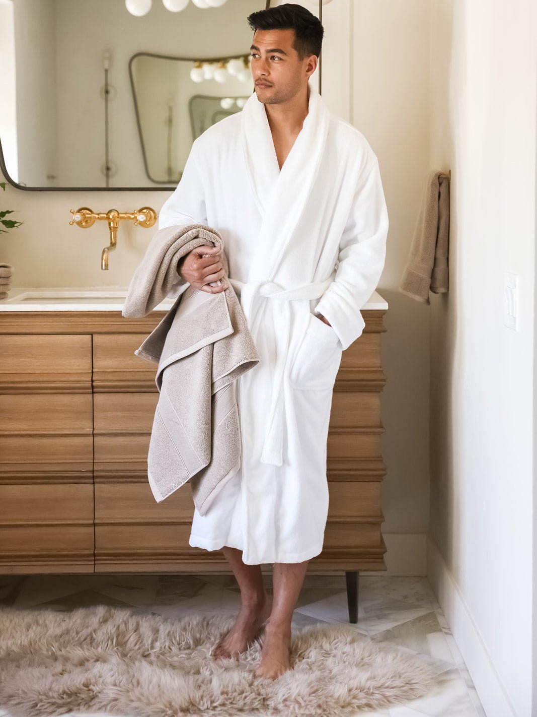 Man in white robe holding sand luxe bath towel 
