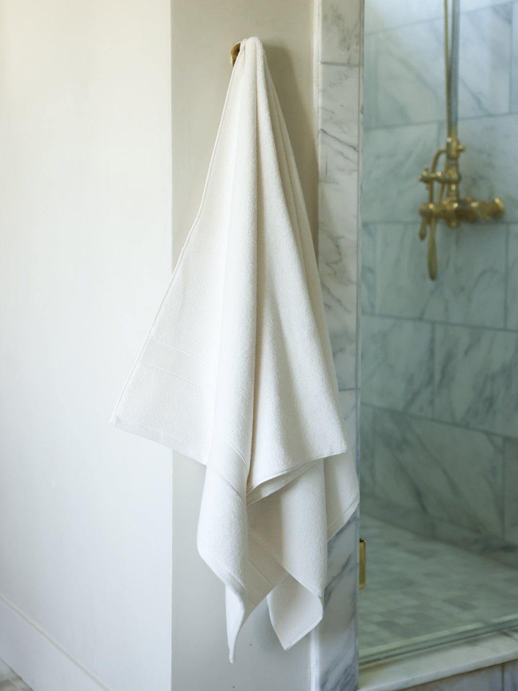 Seashell luxe bath sheet hanging next to shower 