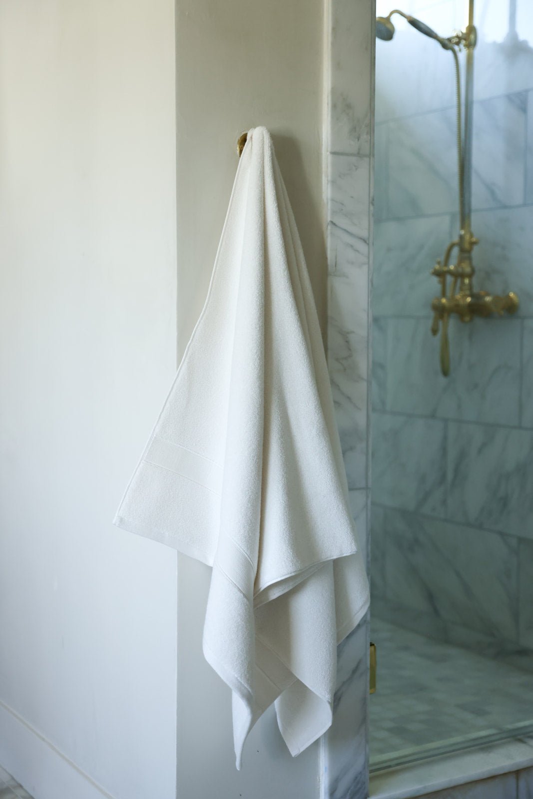 Seashell luxe bath towel hanging next to shower 