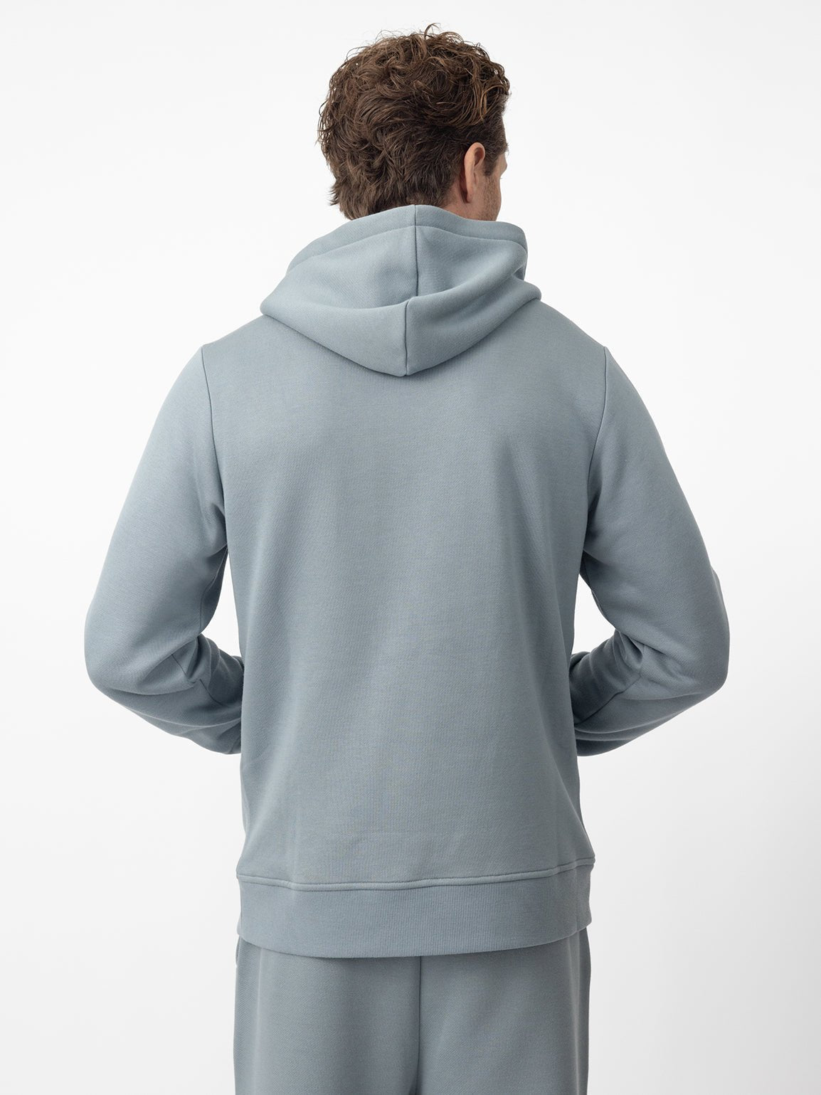 Back of man wearing smokey blue cityscape hoodie with white background