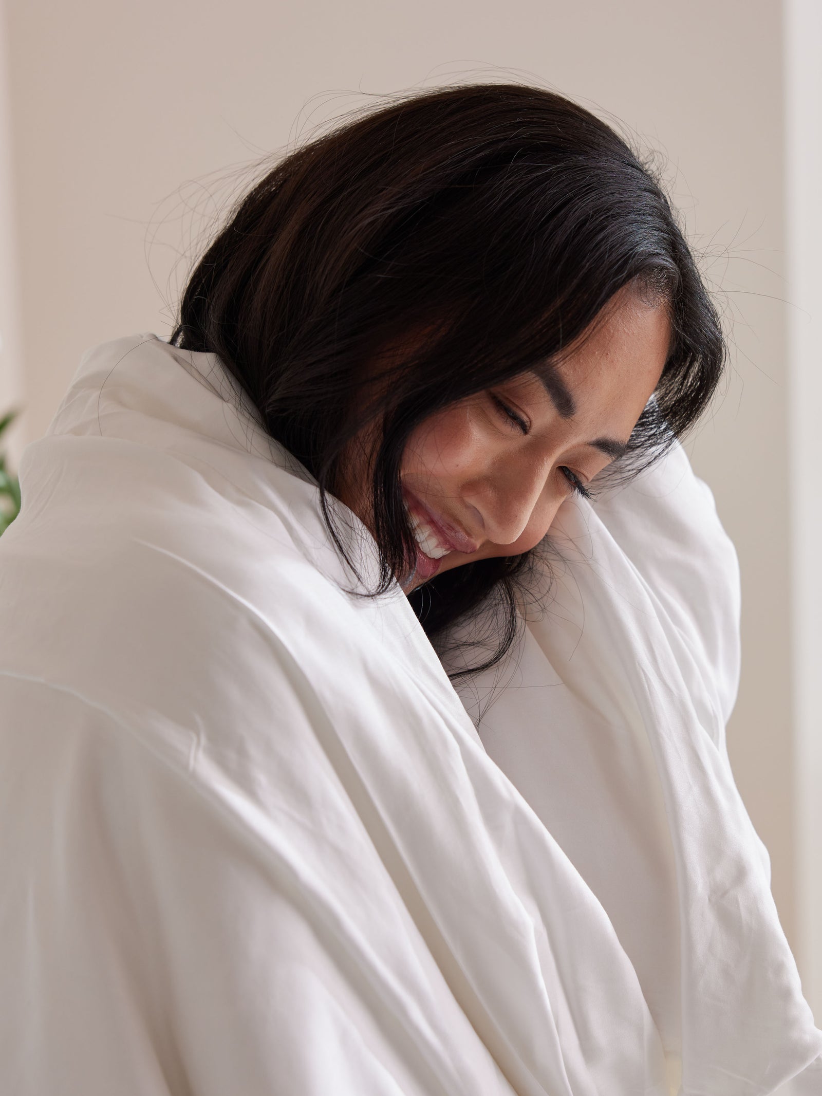 Woman smiling with silk comforter wrapped around her 