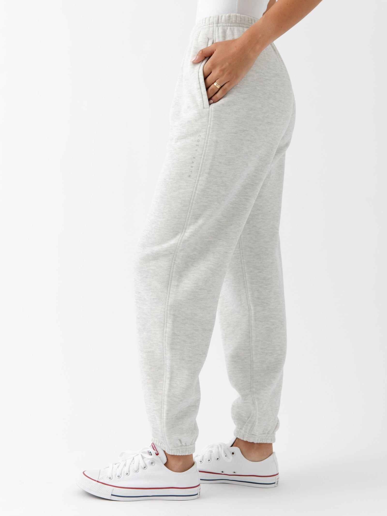 Heather Grey CityScape Joggers. The Joggers are being worn by a female model. The photo is taken from the waist down with the models hand in the pocket of the joggers. The back ground is white.
