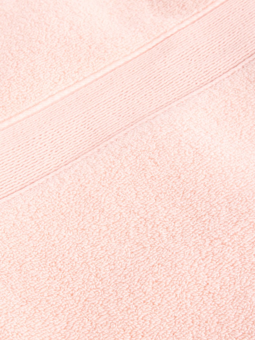 Close-up of the Complete Luxe Bath Bundle by Cozy Earth, showcasing a soft, textured light pink towel with a horizontal band near the top and a woven pattern that enhances its plush appearance.