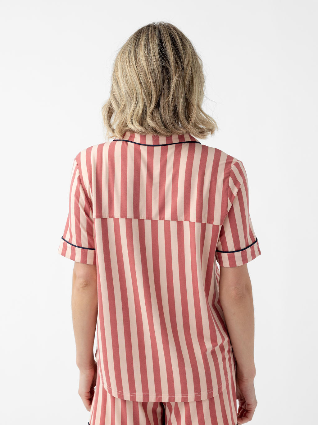 Back of woman wearing blush stripe short sleeve pajama top with white background