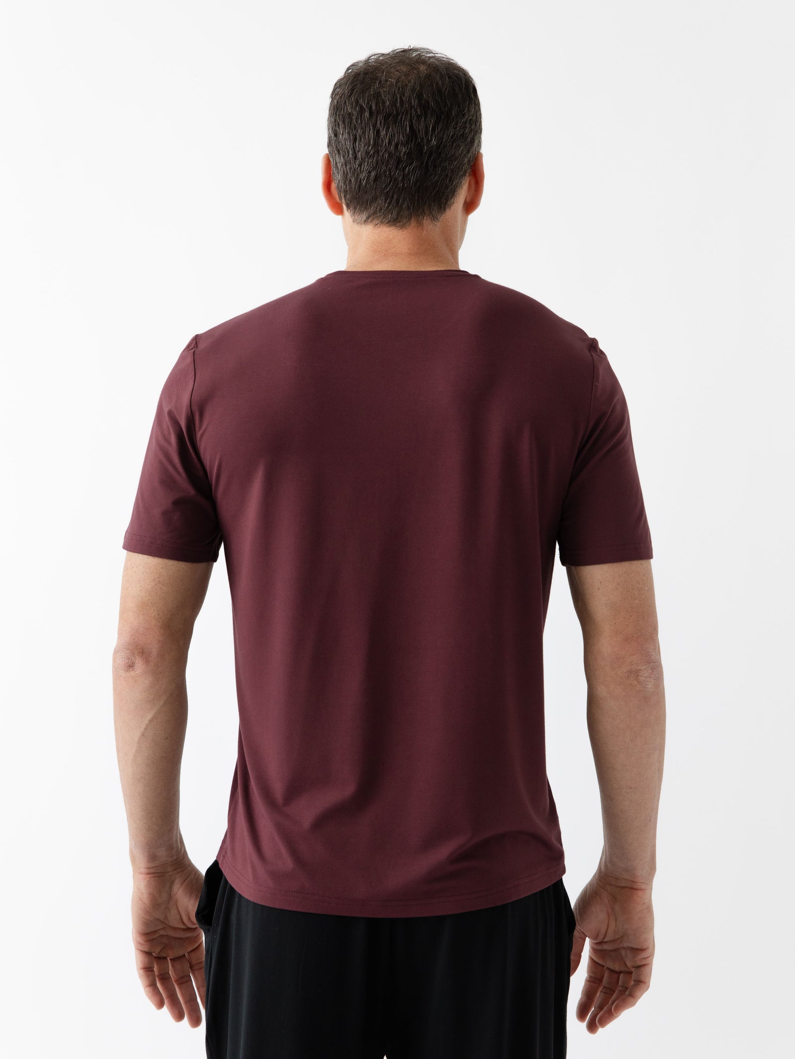 Burgundy Men's Stretch-Knit Bamboo Lounge Tee. A man is wearing the lounge tee in a well lit home with his back facing the camera.
