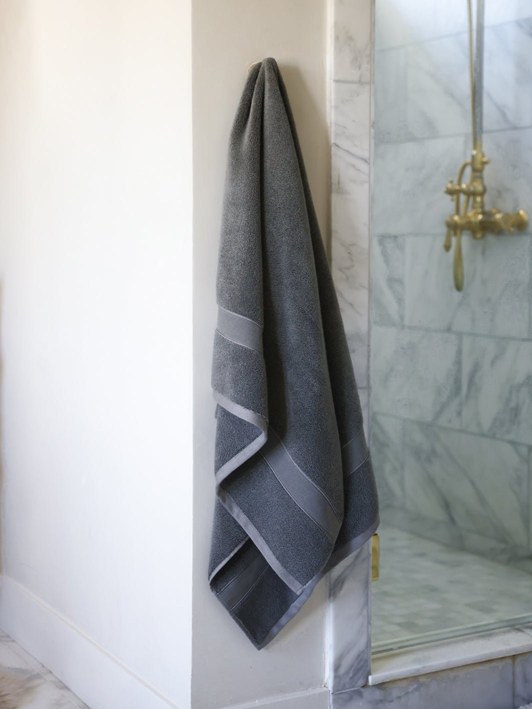 Charcoal luxe bath towel hanging next to shower 