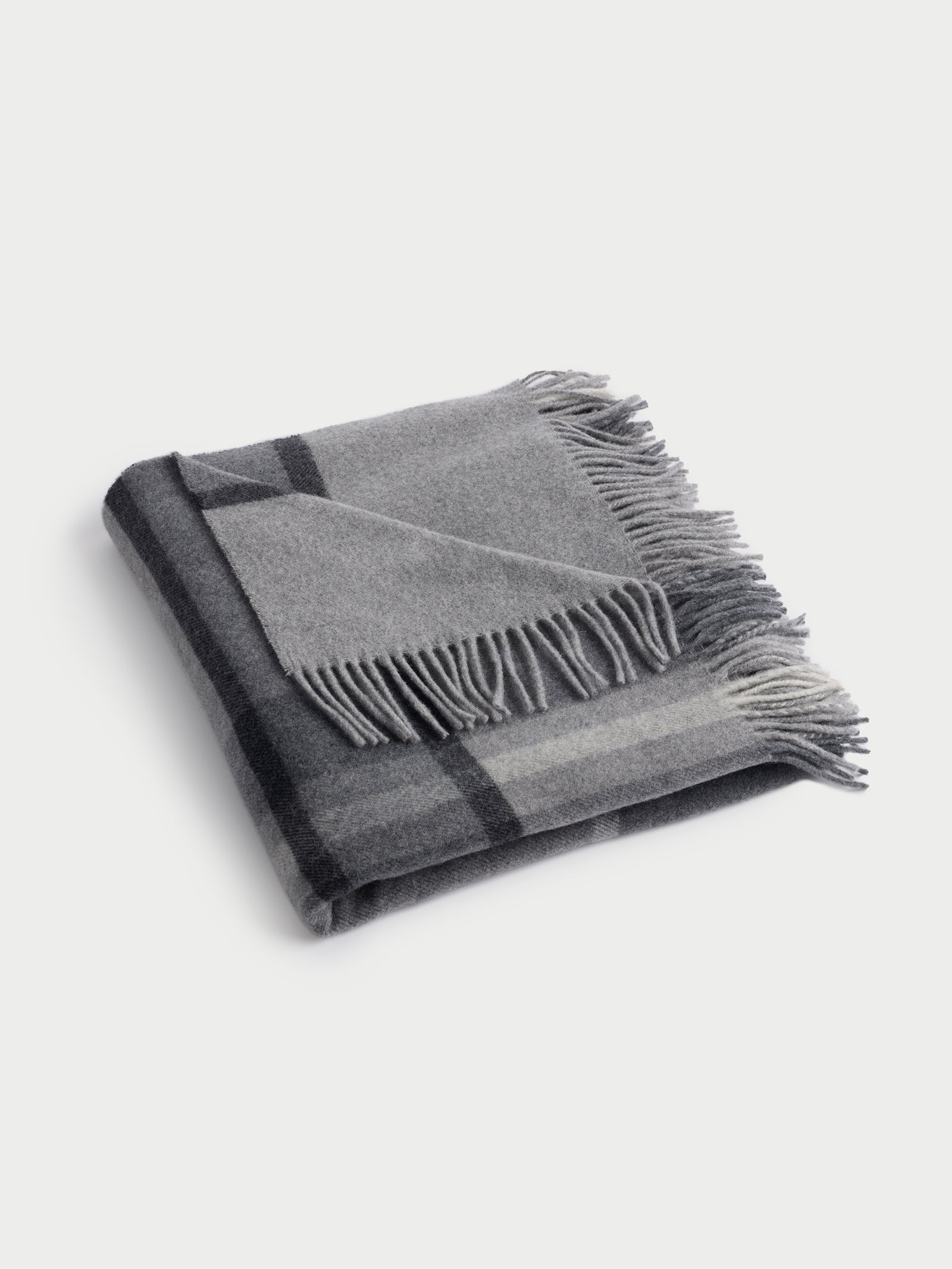 Folded grey lucca throw with white background