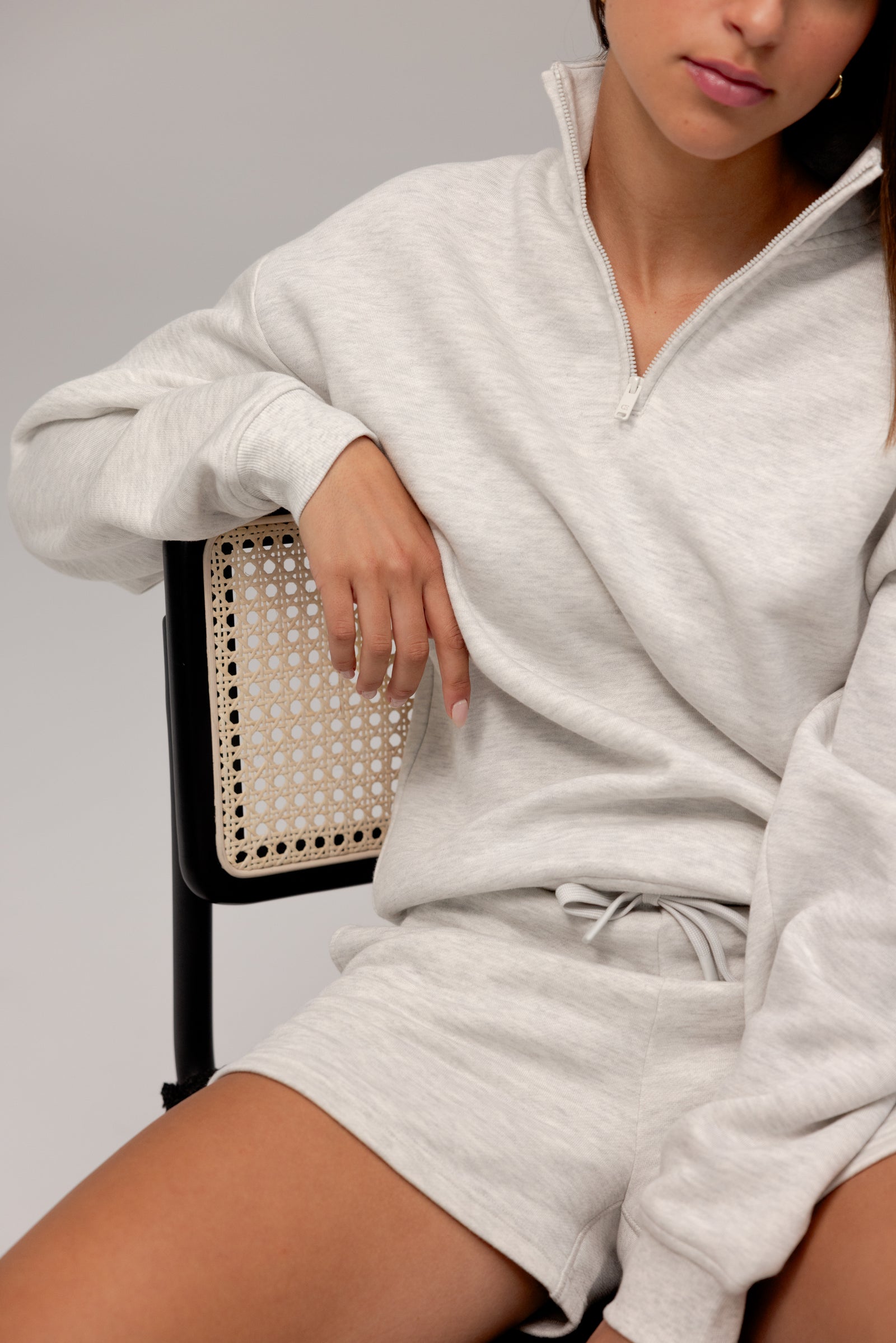 Heather Grey CityScape Quarter Zip. The quarter zip is being worn by a female model. The model is wearing accompanying CityScape clothing to complete the look of the quarter zip. The photo was taken with a grey background.