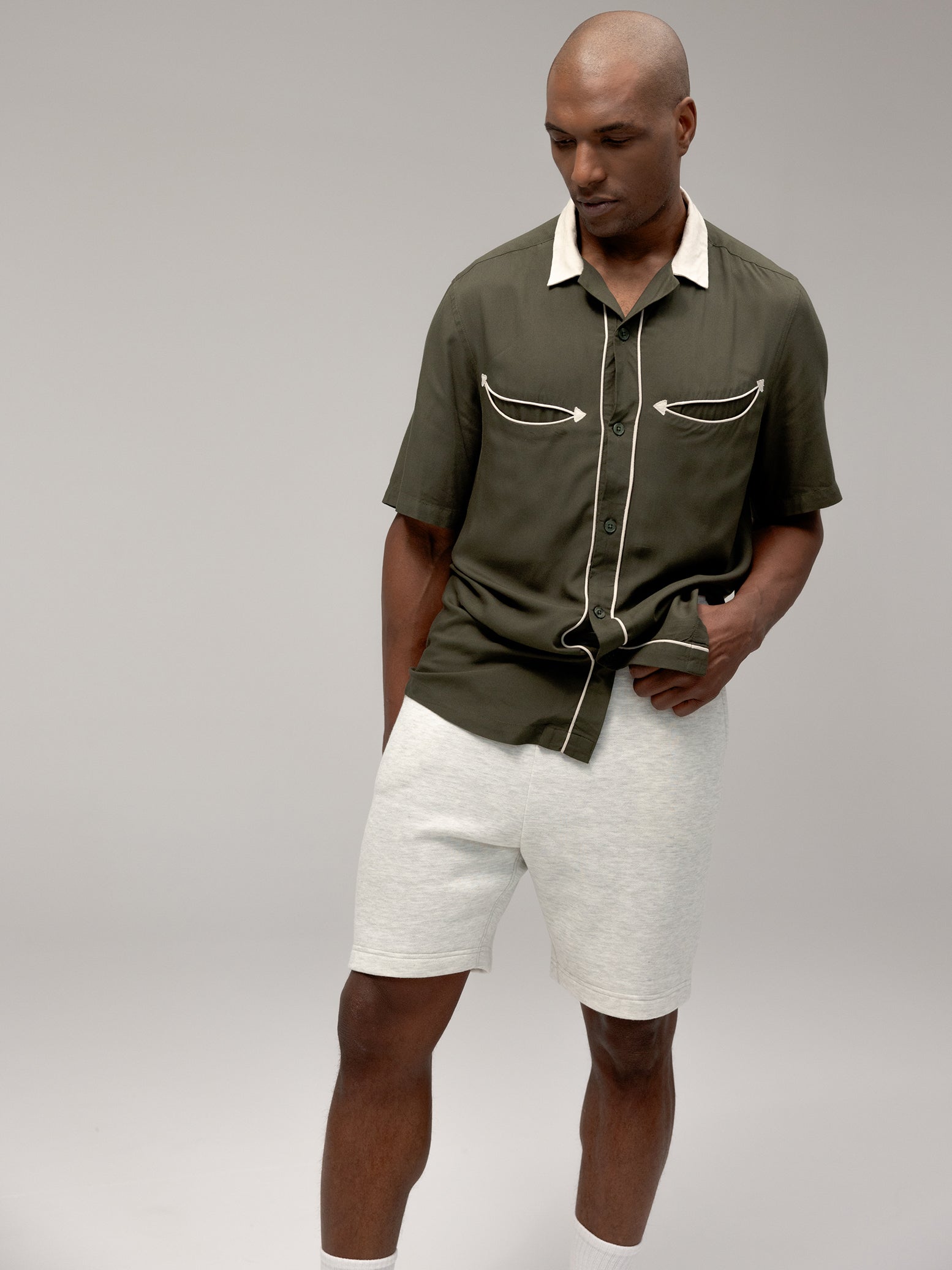 Man wearing heather grey cityscape shorts and dark green button down