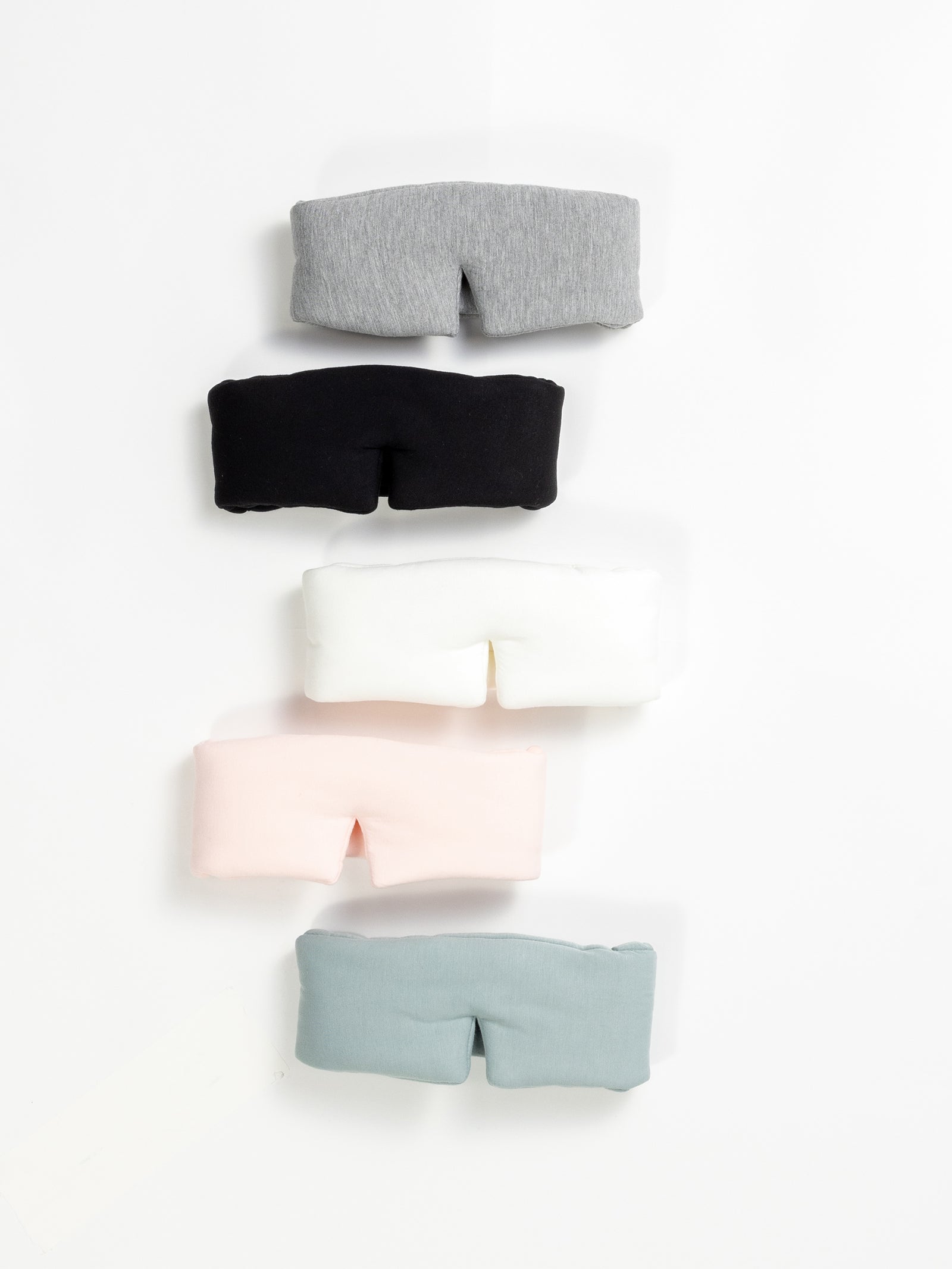 Tthe Cozy Earth Adjustable Bamboo Sleep Masks in Grey, Black, Ivory, Blossom, and Brook are pictured on a white background.