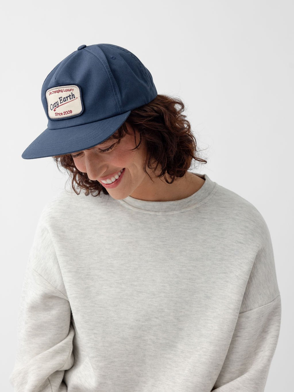 Woman smiling and looking down wearing navy heritage snapback 