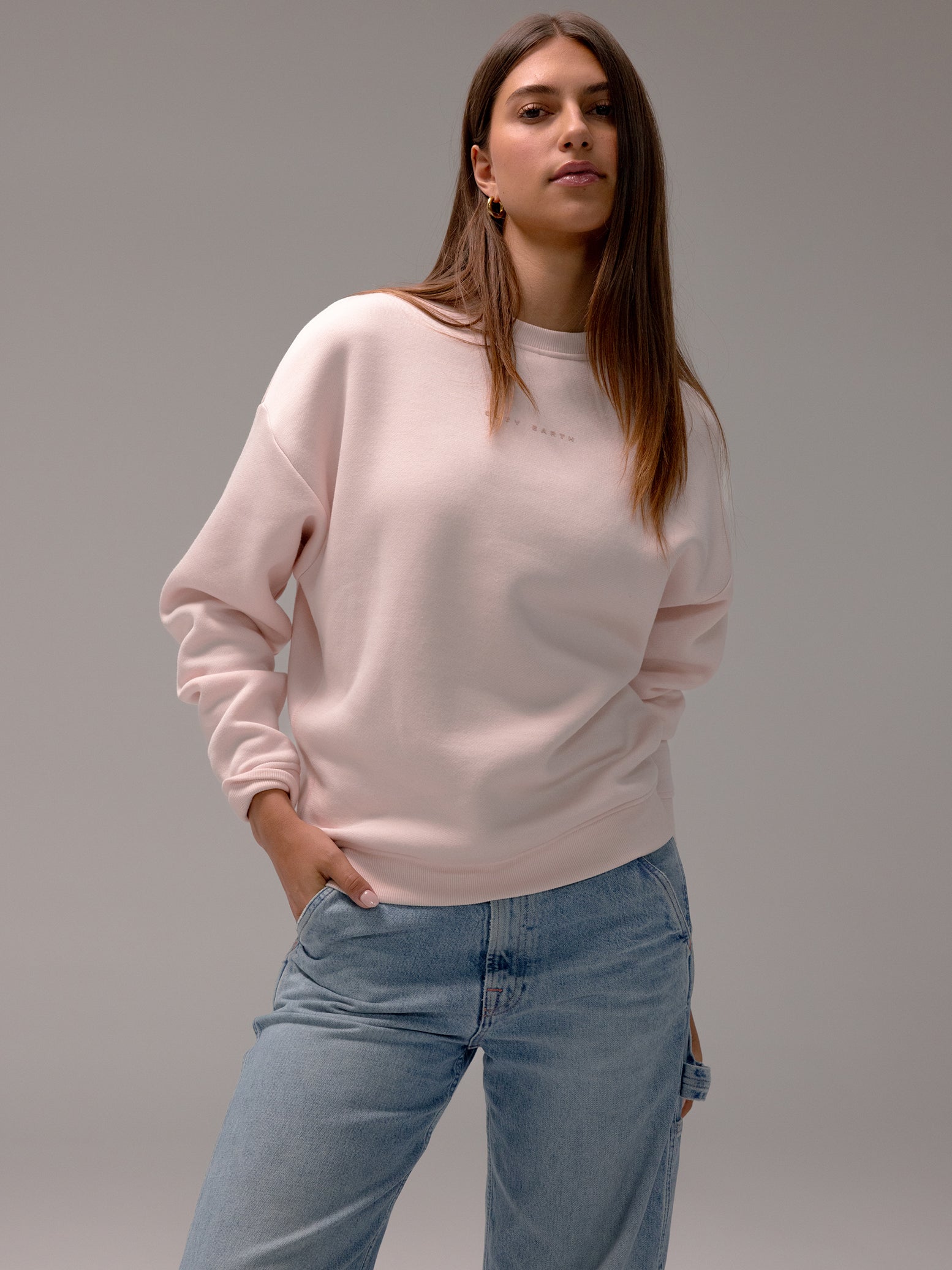 Peony CityScape Pullover Crew. The Pullover is being worn by a female model. An accompanying pair of jeans is being worn to complete the look of the outfit. The photo was taken with a white background. 