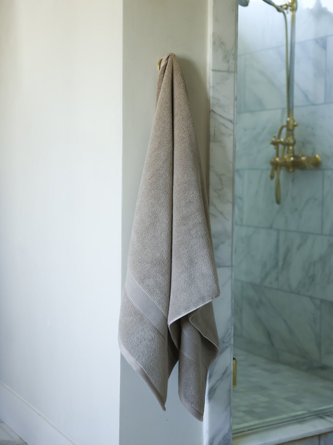Sand luxe bath sheet hanging next to shower 