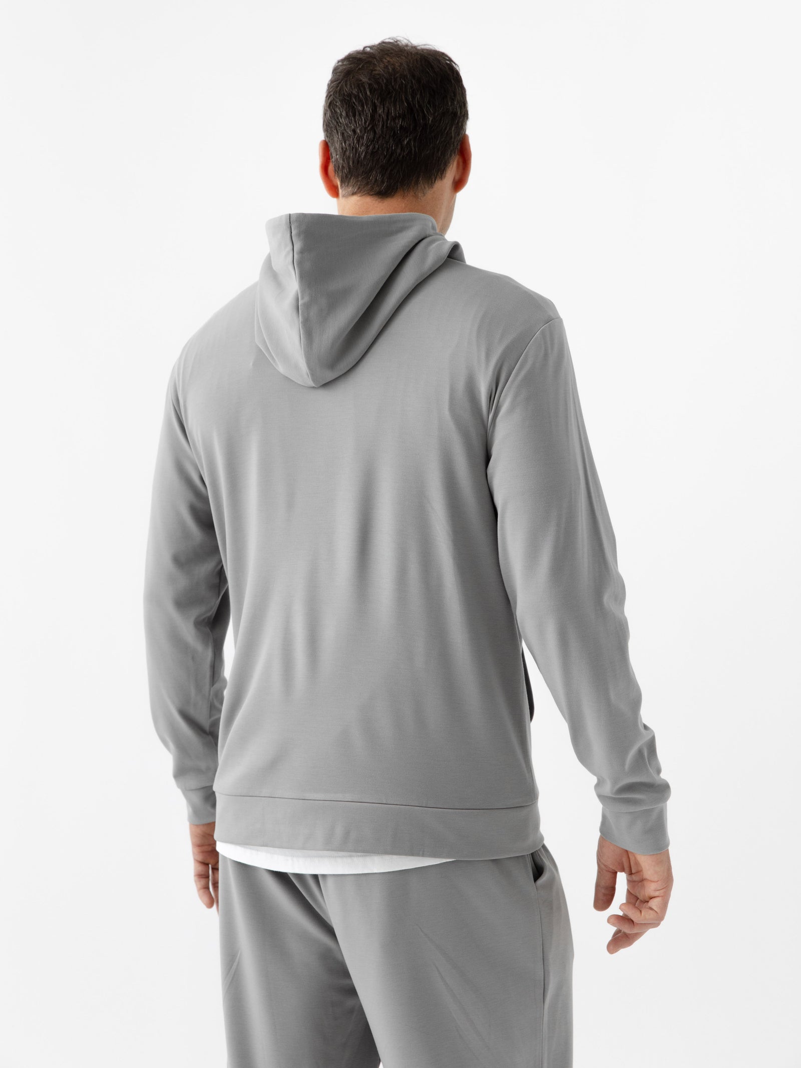 Stone Bamboo Hoodie worn by man standing in front of white background with his back facing the camera.