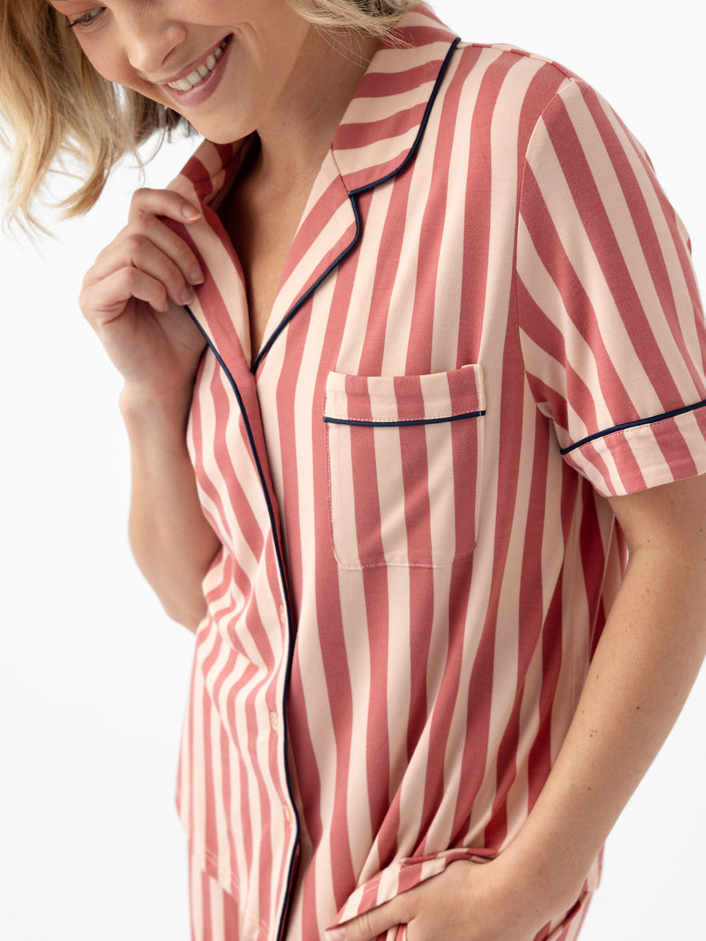 Woman wearing blush stripe short sleeve pajama top with white background