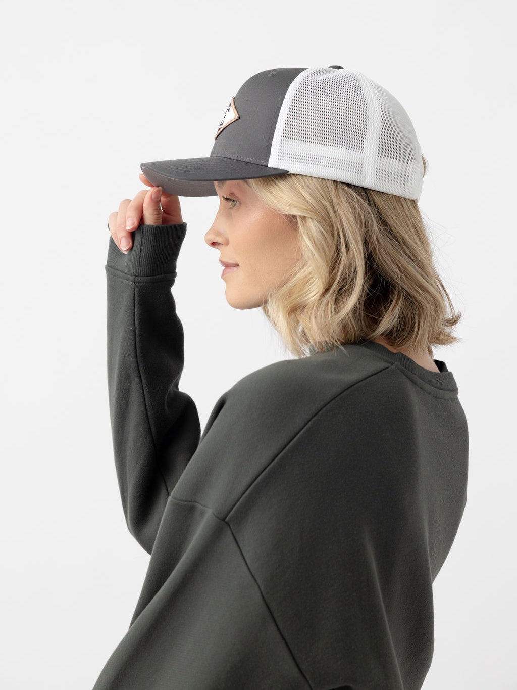 Side view of woman wearing charcoal/white diamond mesh trucker hat 
