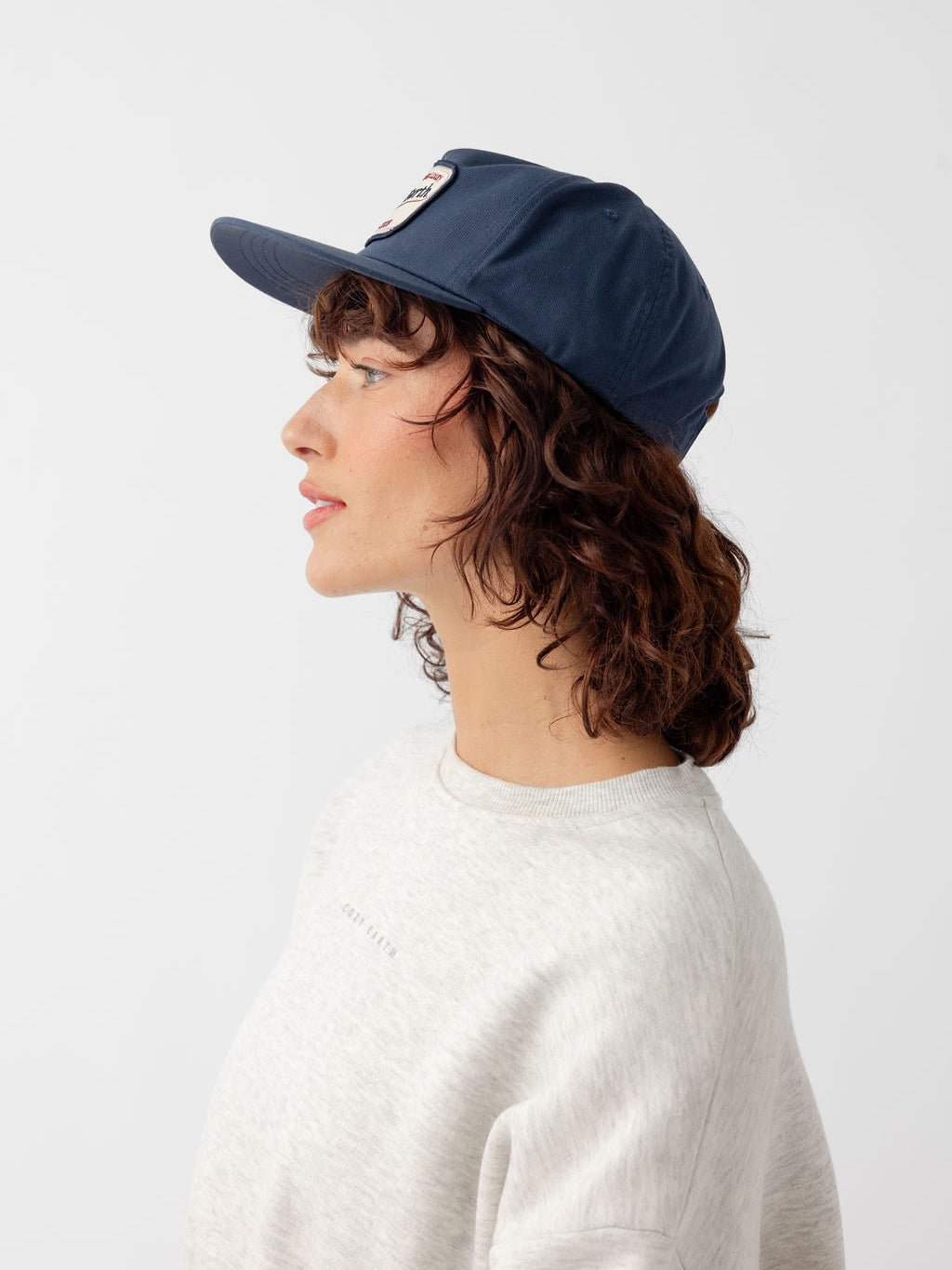 Side view of woman wearing navy heritage snapback 