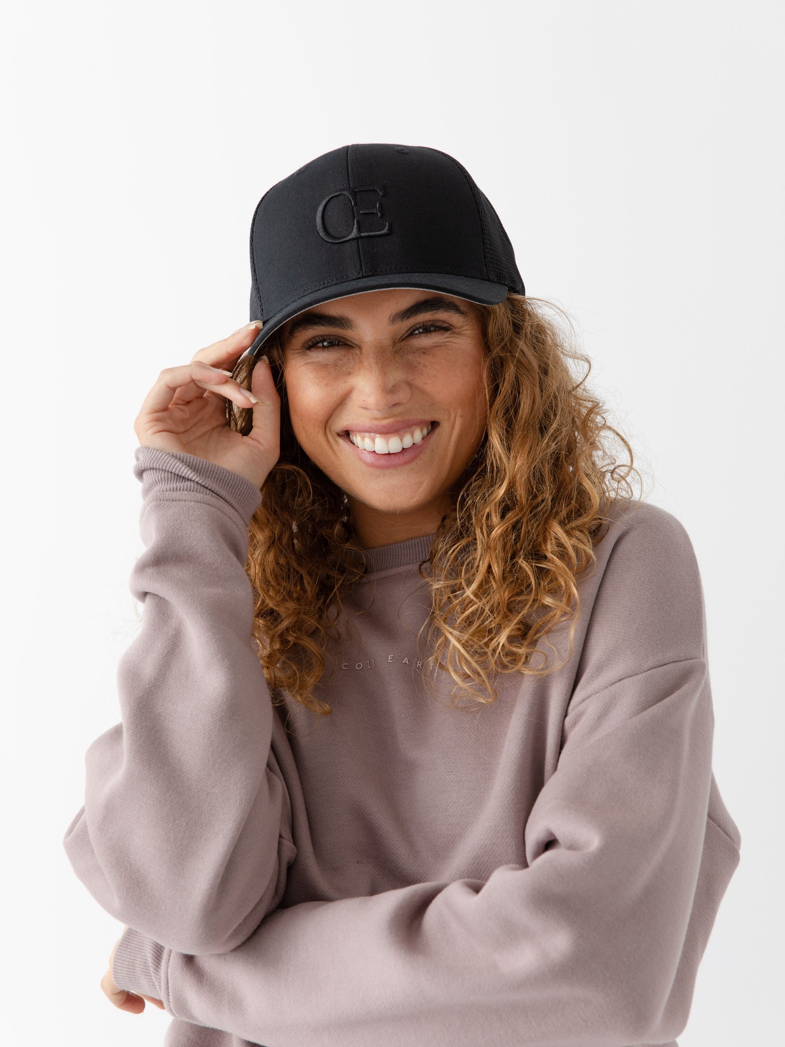 Woman wearing a black cap with a CE logo on a light gray background