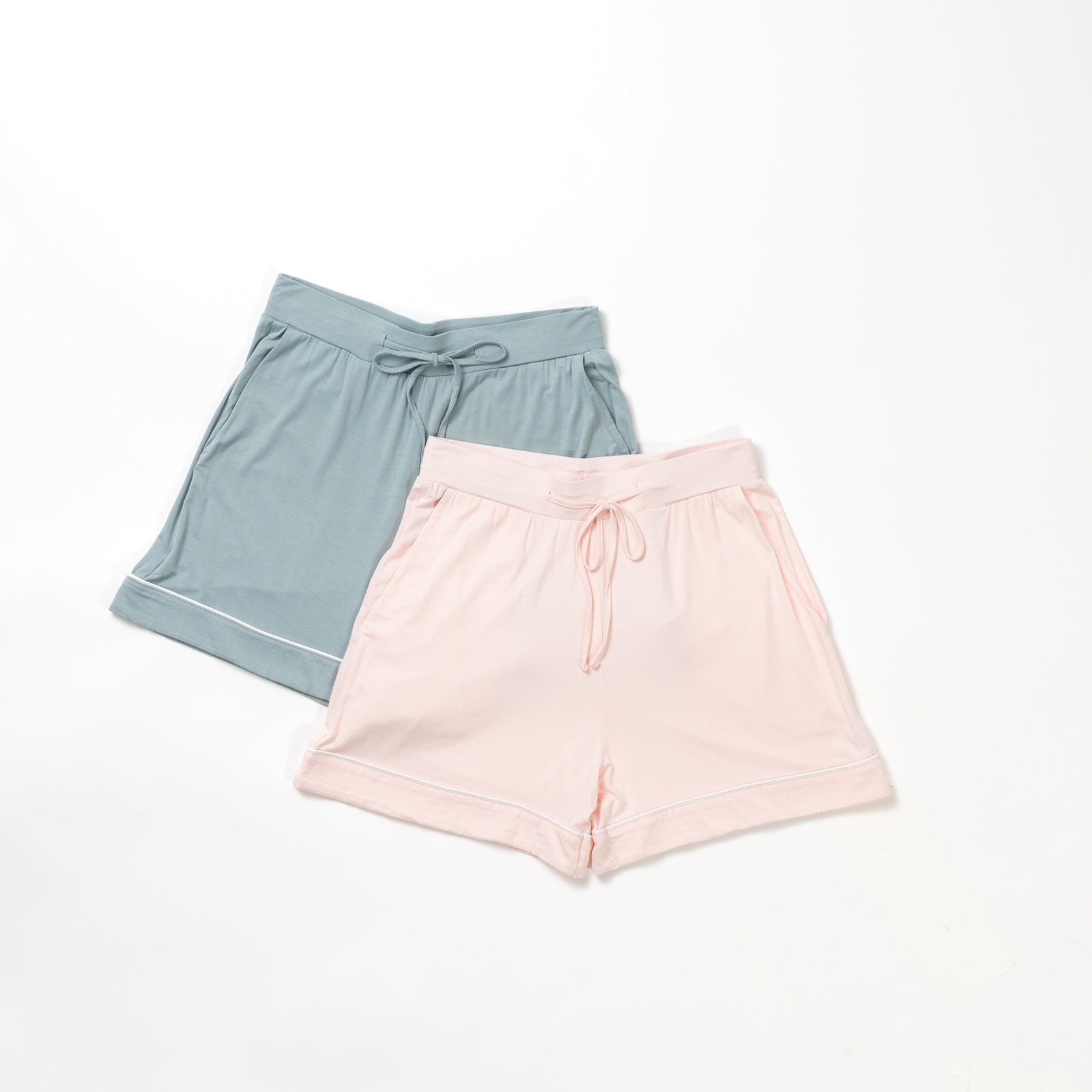 Displayed on a white background are two pairs of the Women's Bamboo Pajama Shorts from HIDE. One pair is light teal, and the other is soft pink. Both have a comfortable, loose fit and feature an adjustable drawstring waist.