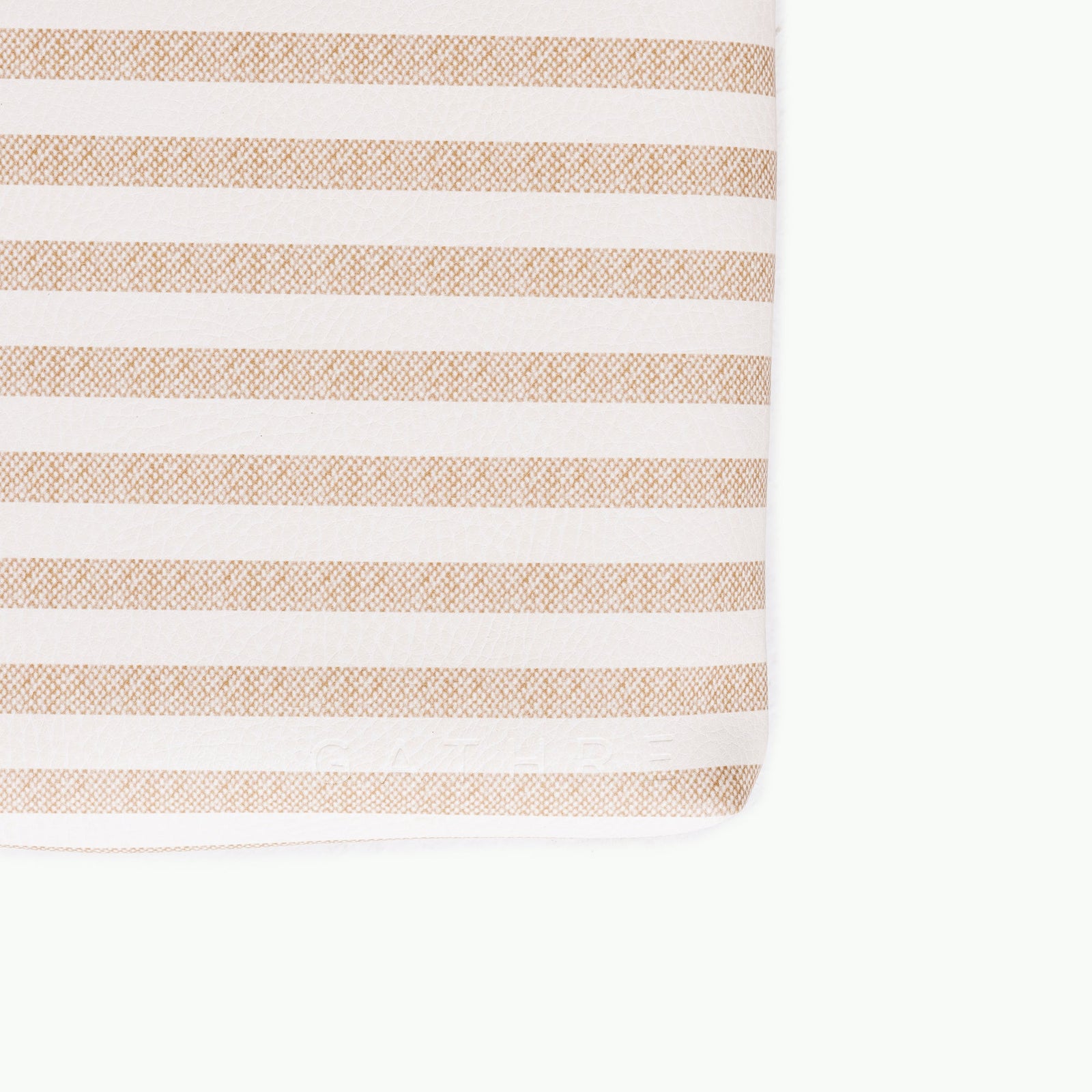 A close-up of the Gathre Wholesale Padded Changing Mat, featuring horizontal beige and white stripes, displays its soft texture and neatly finished edge at the bottom right.
