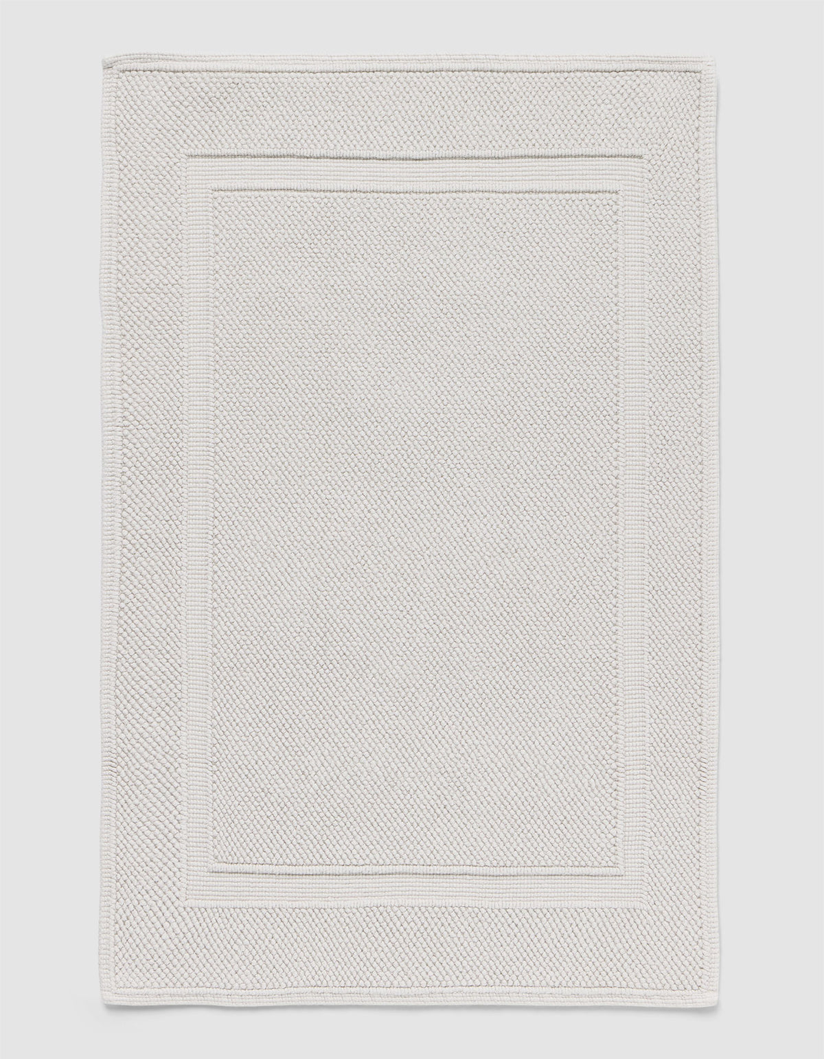 The Cozy Earth Classic Bath Mat features a rectangular shape, light color, subtle textured pattern, and elegant double border design on the edges.|Color:Light Grey