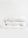 A neatly folded Down Alternative Comforter by Cozy Earth is placed against a plain background. The quilted texture is visible, highlighting its fluffy and soft appearance. |Filling:Standard