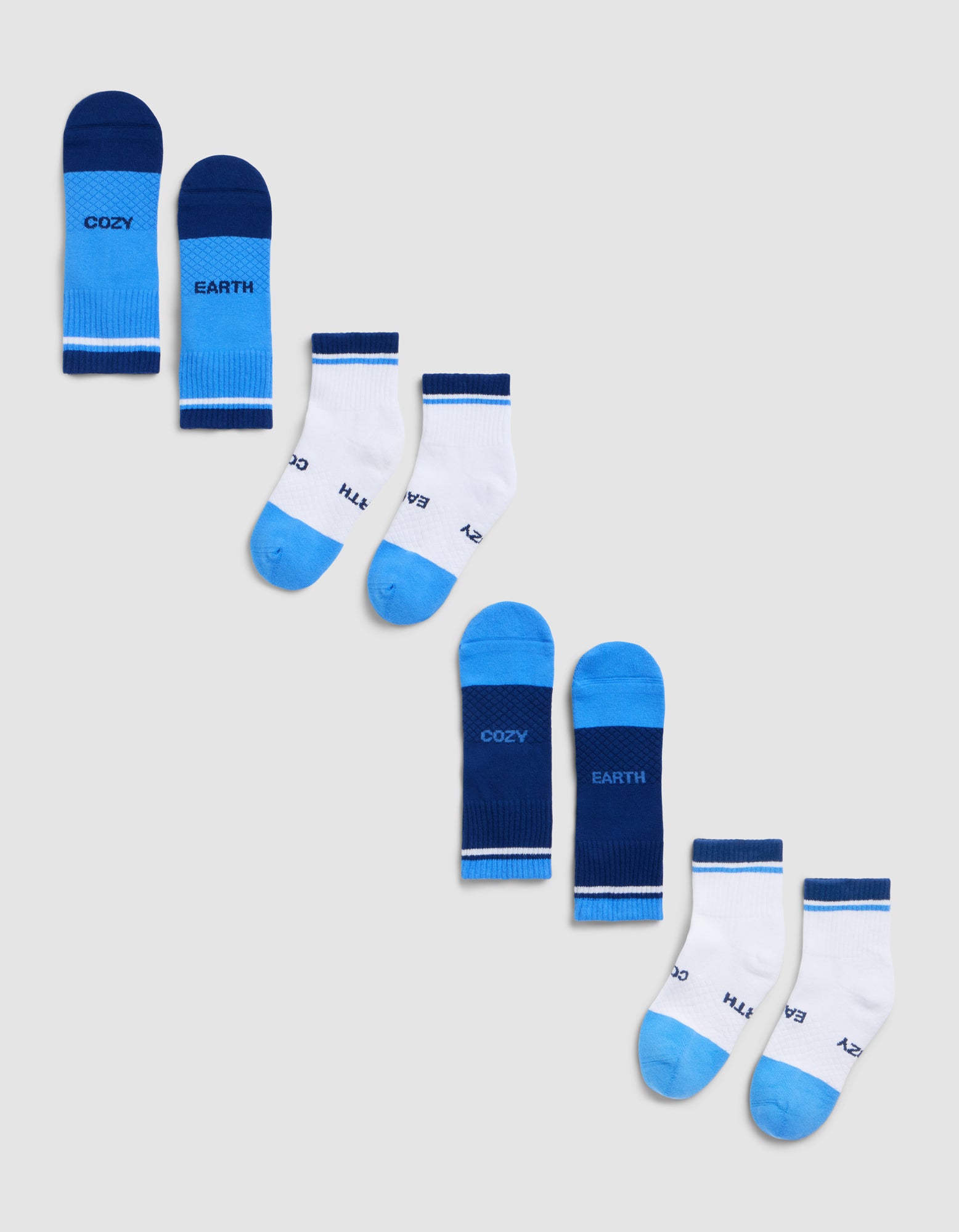 Four pairs of children’s socks from Cozy Earth’s Essential Quarter Sock 4-Pack are arranged diagonally on a light gray background, featuring white and blue colors with "COZY" and "EARTH" written on them. |Color:Harbor