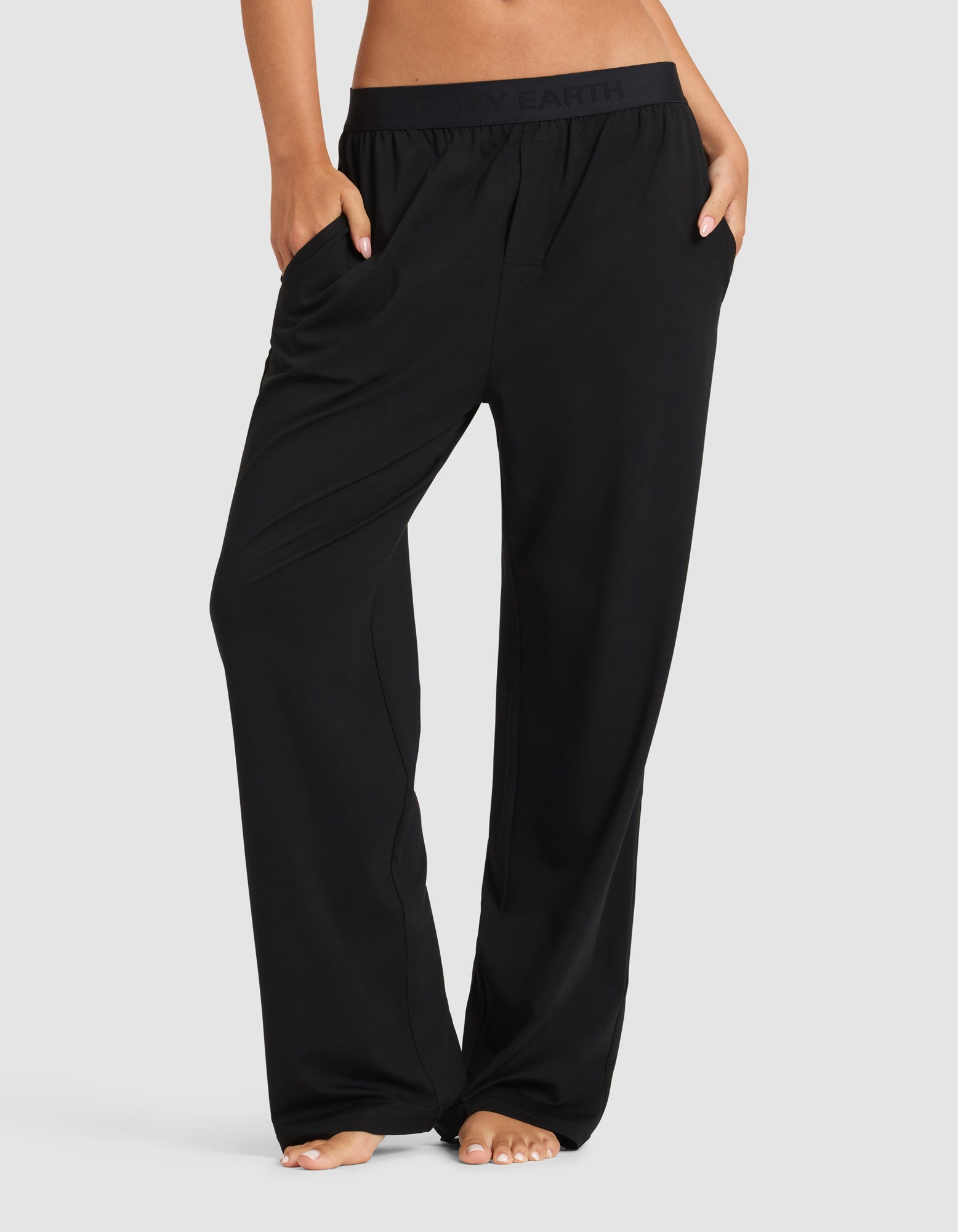 A woman stands barefoot with hands in her pockets, modeling Cozy Earth’s Women's First Layer Pajama Pant. Only the lower half of her body is visible against a plain light background.