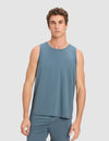 A young man with short, curly brown hair wears the Cozy Earth Men's First Layer Pajama Tank in blue, paired with matching shorts, standing against a plain light gray background and looking directly at the camera.|Color:Dawn