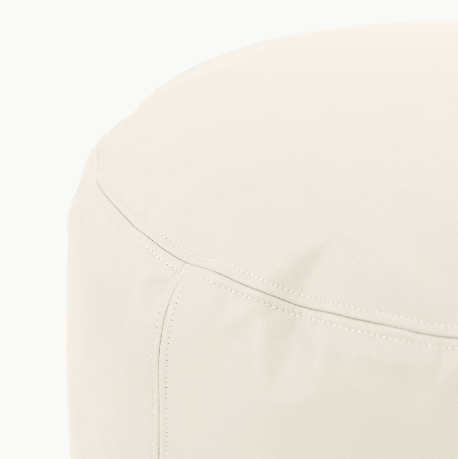 A close-up of the Gathre Wholesale Pouf, a cream-colored, round leather ottoman highlighting fine stitching and smooth surface texture.