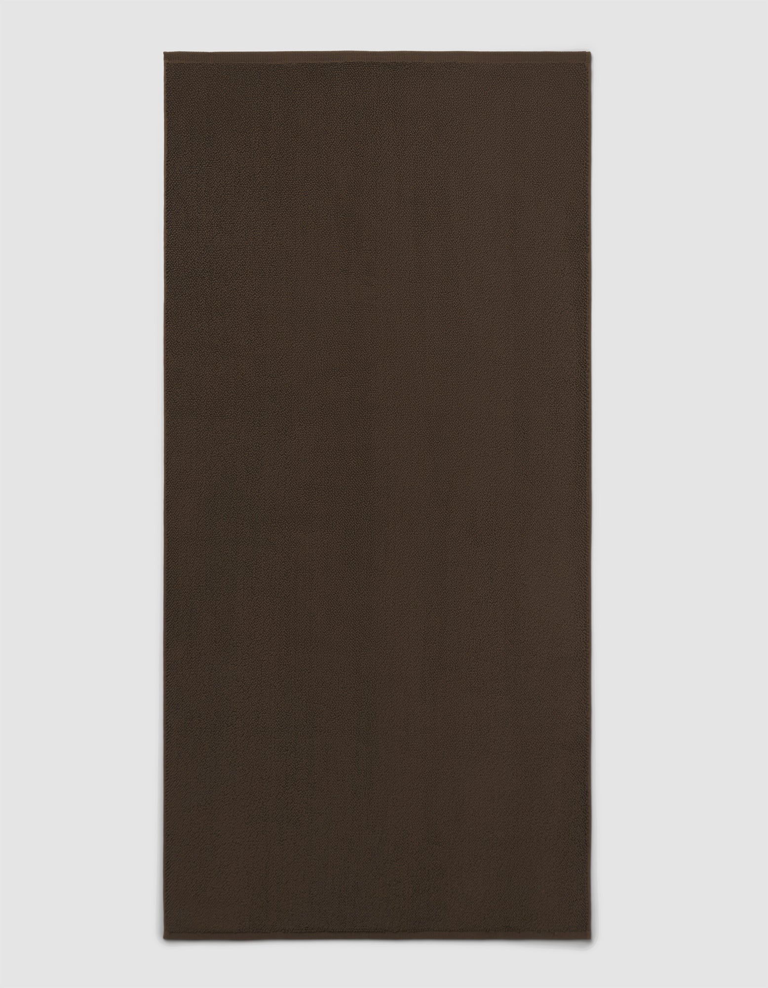 The Cozy Earth Loop Terry Bath Mat is shown on a light gray background. This plain, rectangular bath mat features a dark brown, solid color design without patterns or visible texture.