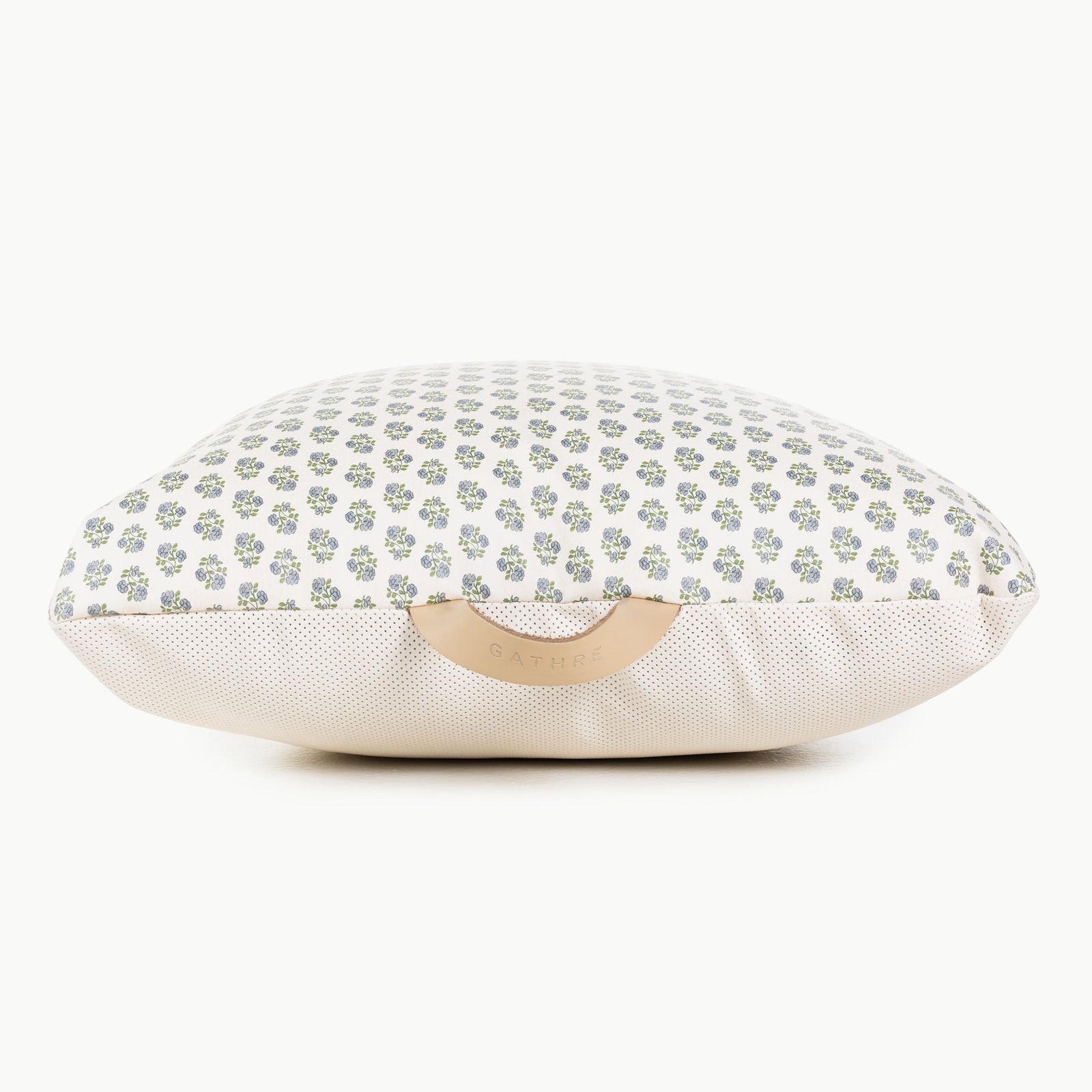 The Gathre Wholesale Floor Cushion features a white surface with small green and purple floral patterns, a beige textured bottom, and a tan leather handle embossed with the brand name.