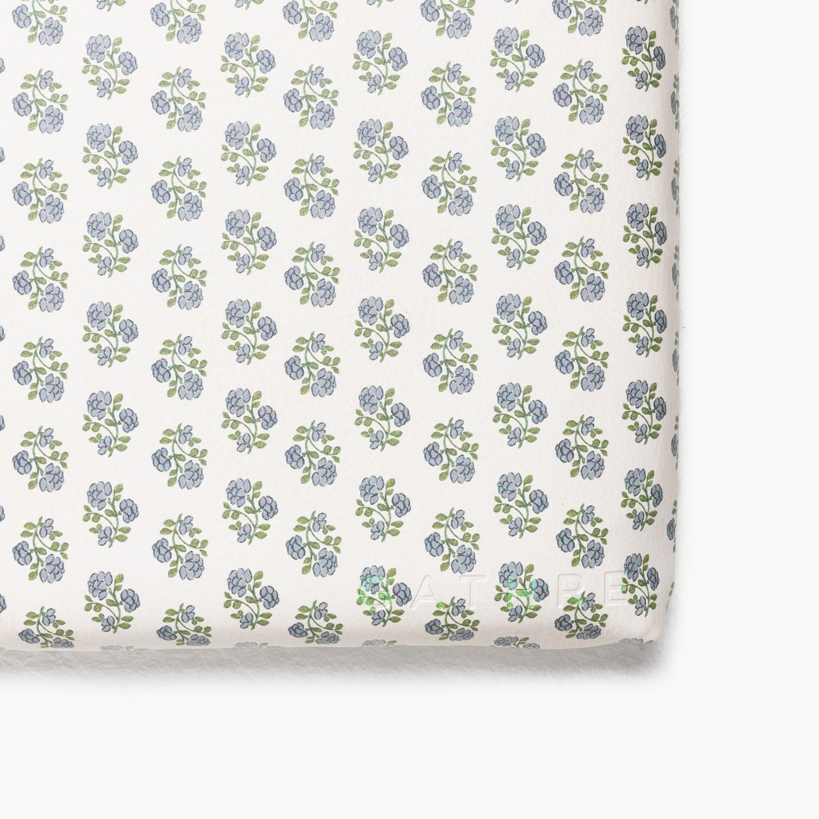 A close-up of the Gathre Wholesale Padded Changing Mat shows its smooth, soft surface with a repeating design of small blue flowers and green leaves.