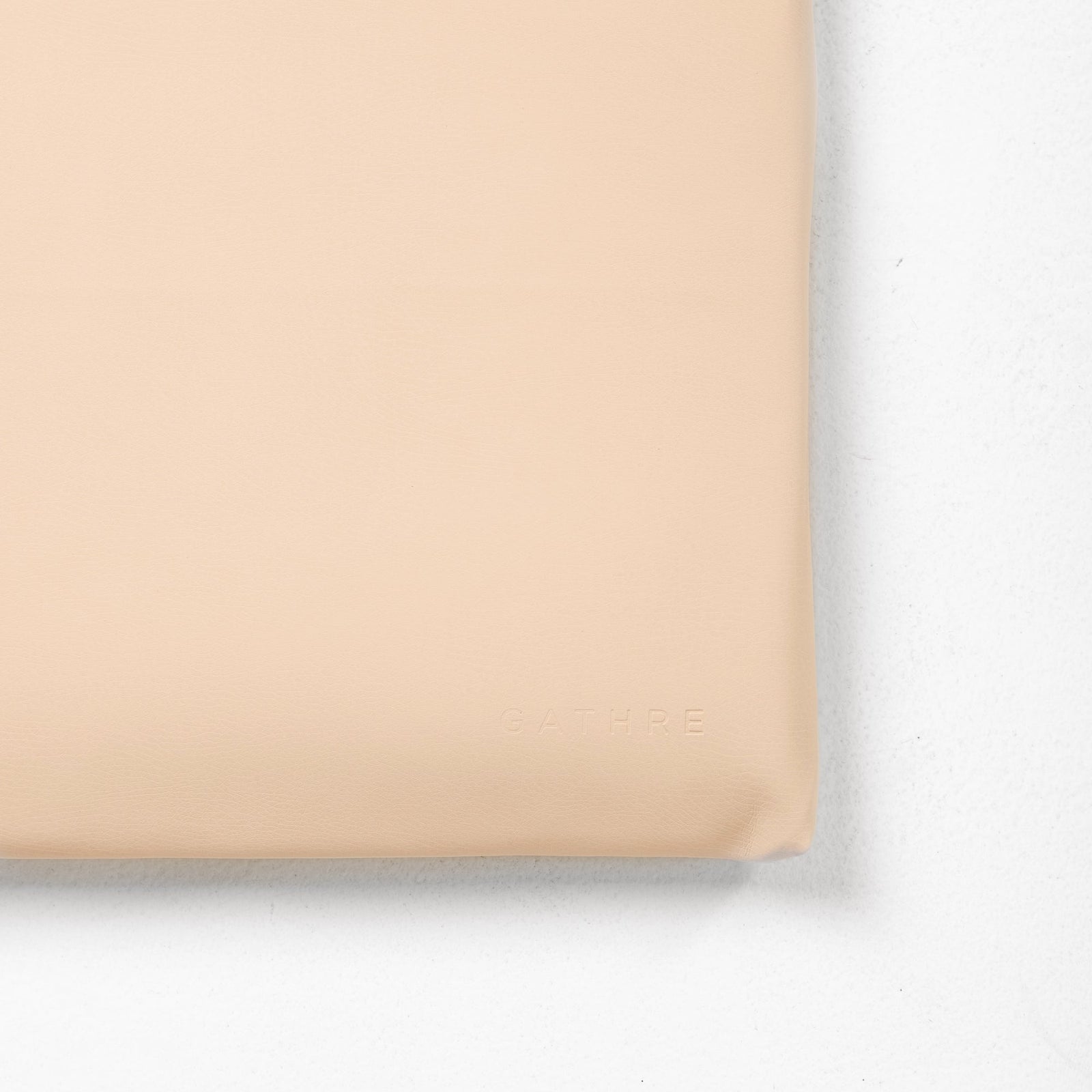 A close-up of the beige Wholesale Padded Changing Mat by Gathre, featuring a subtle "GATHRE" embossing in the bottom right corner, placed on a white surface.