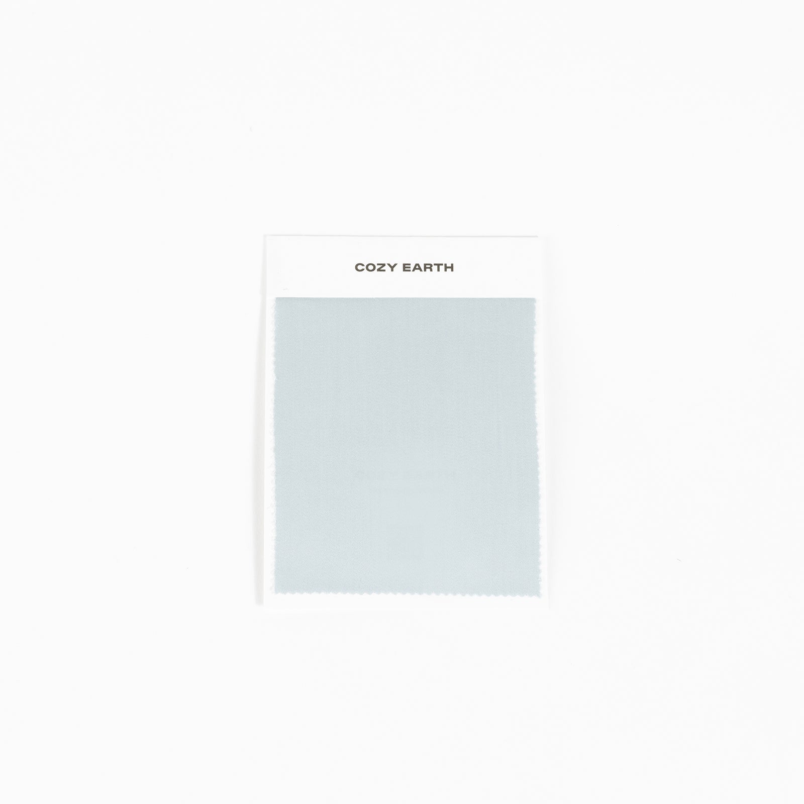 A sample of the bamboo sheet fabric in light gray is displayed against a white background, mounted on a card labeled with "Cozy Earth" at the top.