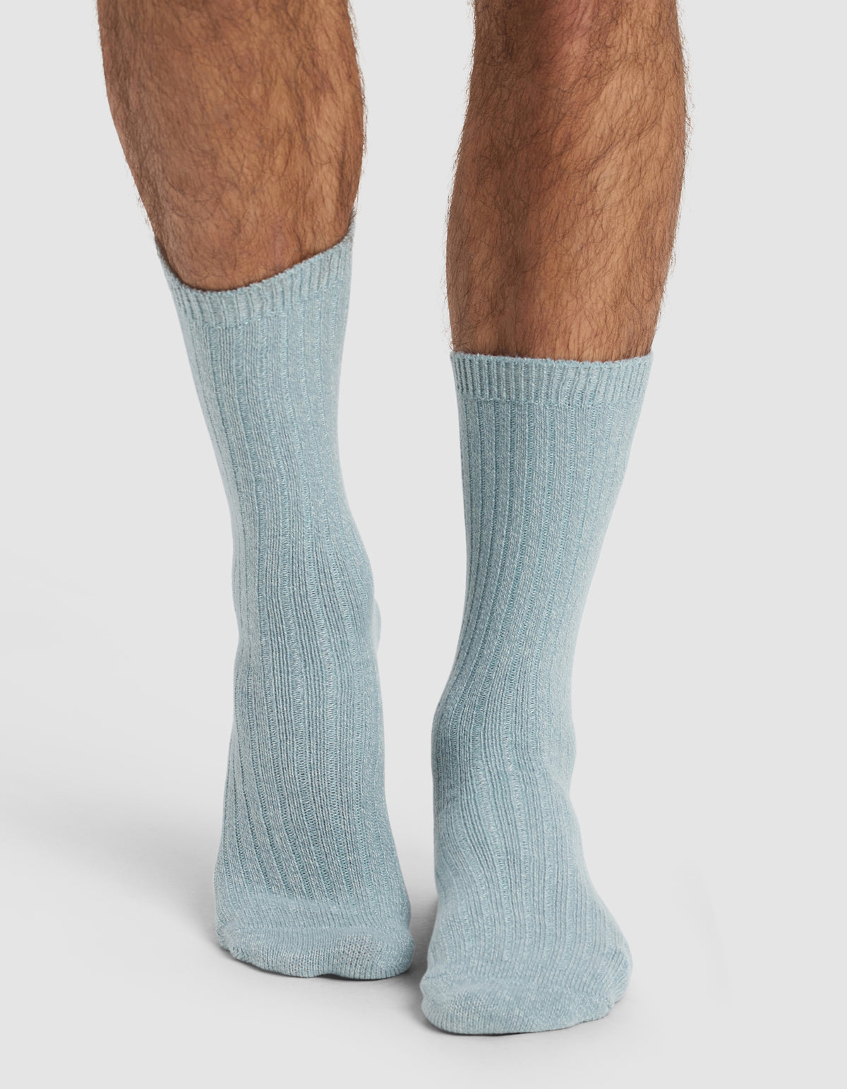 A pair of lower legs wearing Cozy Earth’s The Plush Lounge Sock 3-Pack in light blue, ribbed, mid-calf style, set against a plain white background.
