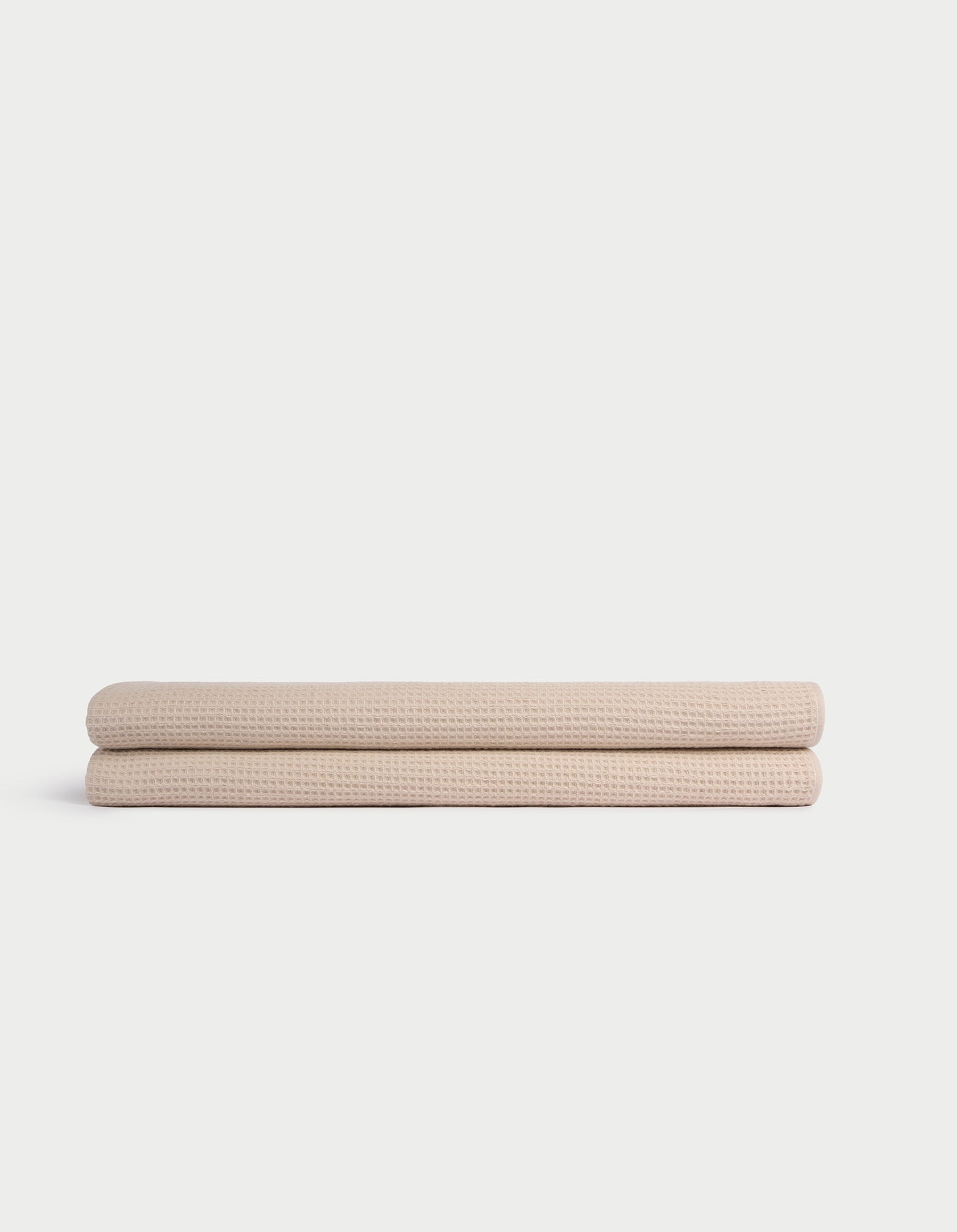 Two Cozy Earth Waffle Bath Sheets, beige and neatly folded, are stacked atop one another against a plain white background. |Color:Birch